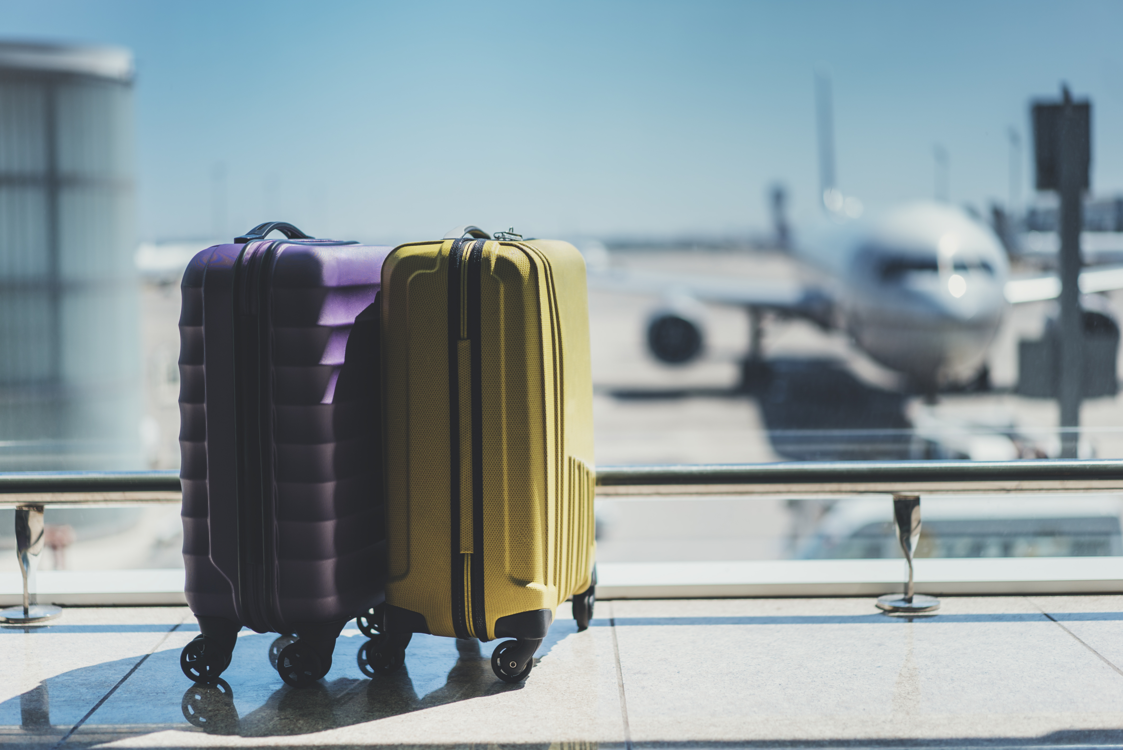 Suitcases in airport departure lounge, airplane in background