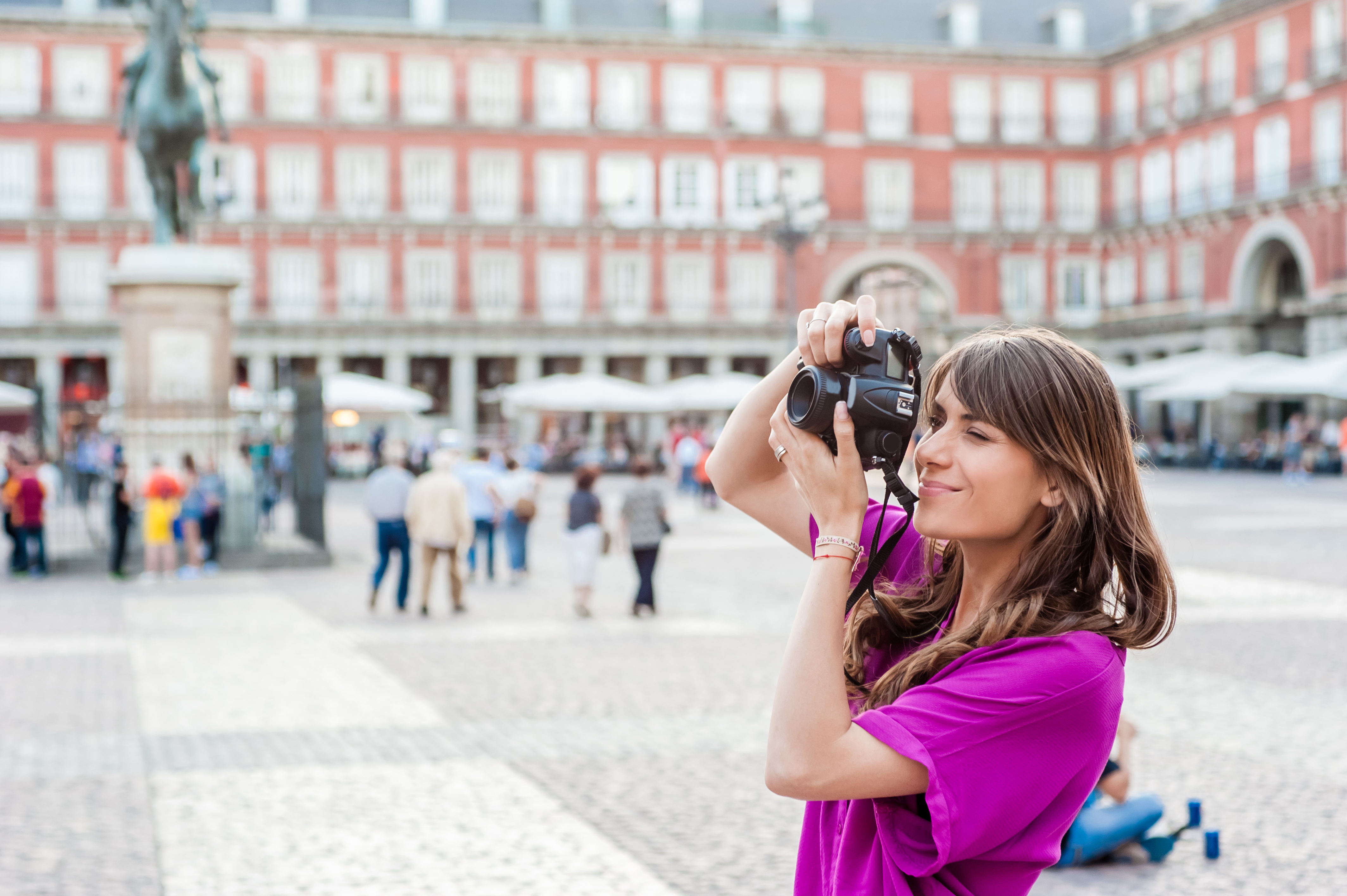 Young woman a photo camera and taking picture in Plaza Mayor square, Madrid
