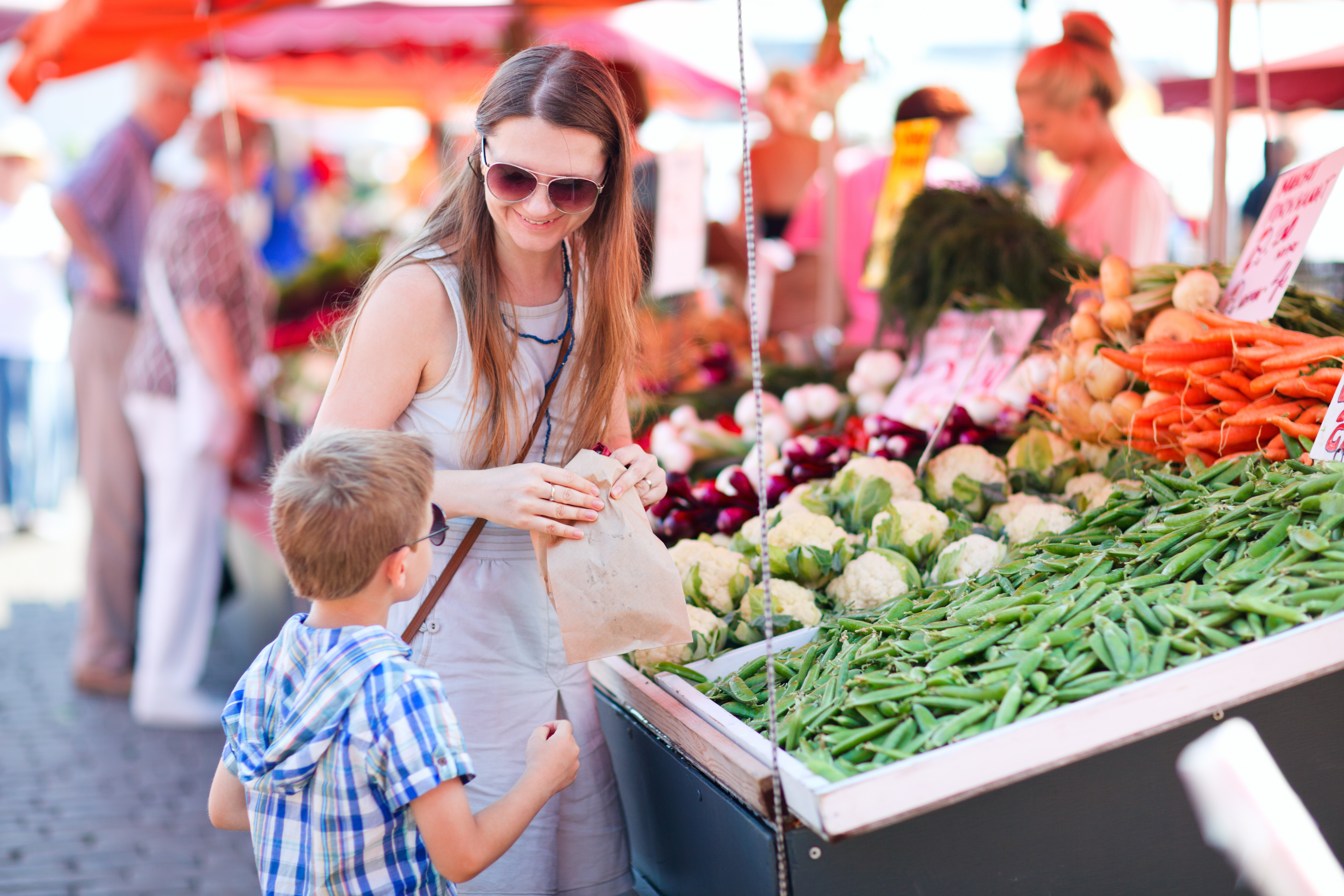 Mother and son buying green peas at market