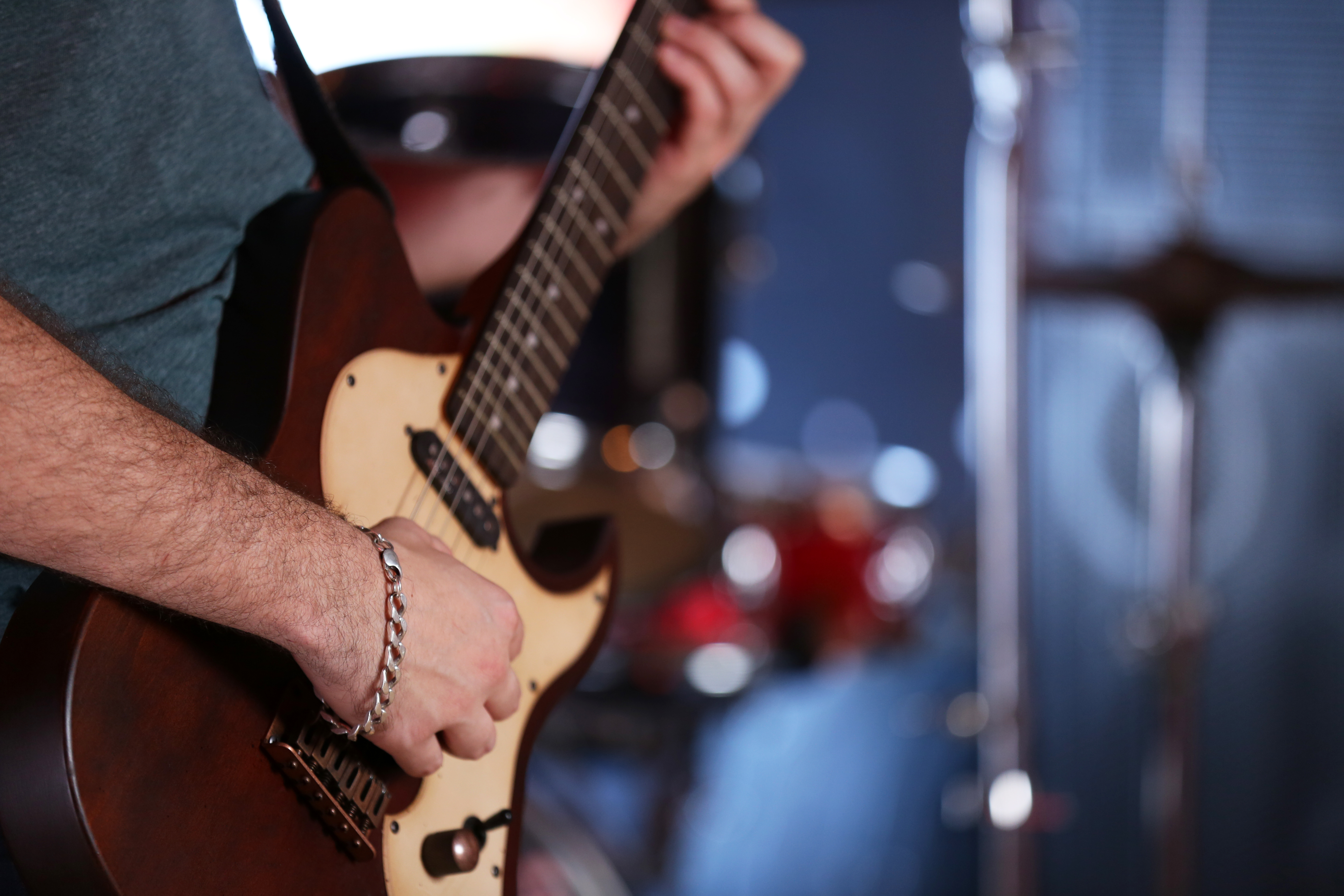 Young man playing on electric guitar close up
