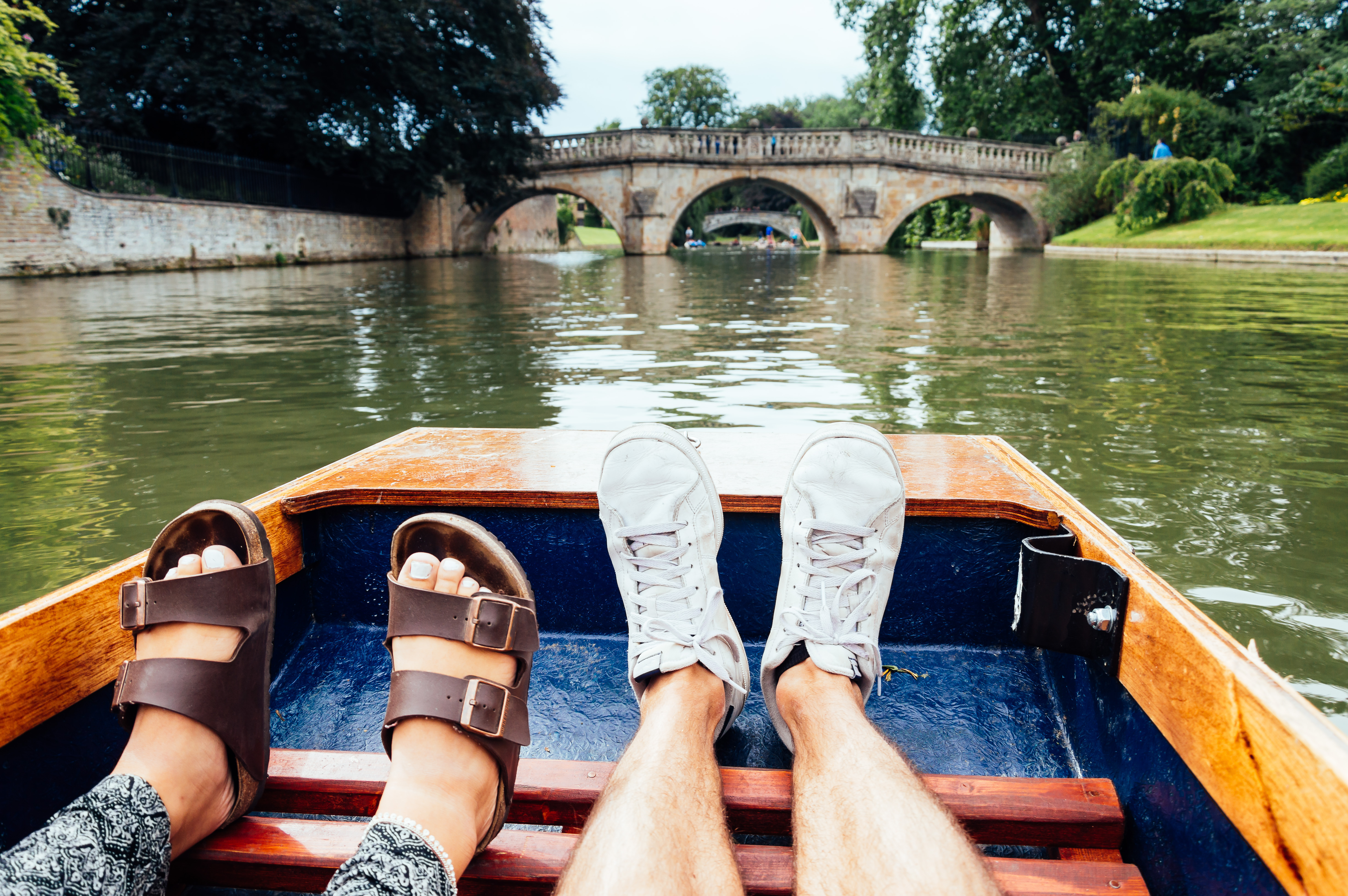 Man and woman feet on a boat punting in the river in Cambridge. Focus on feet.