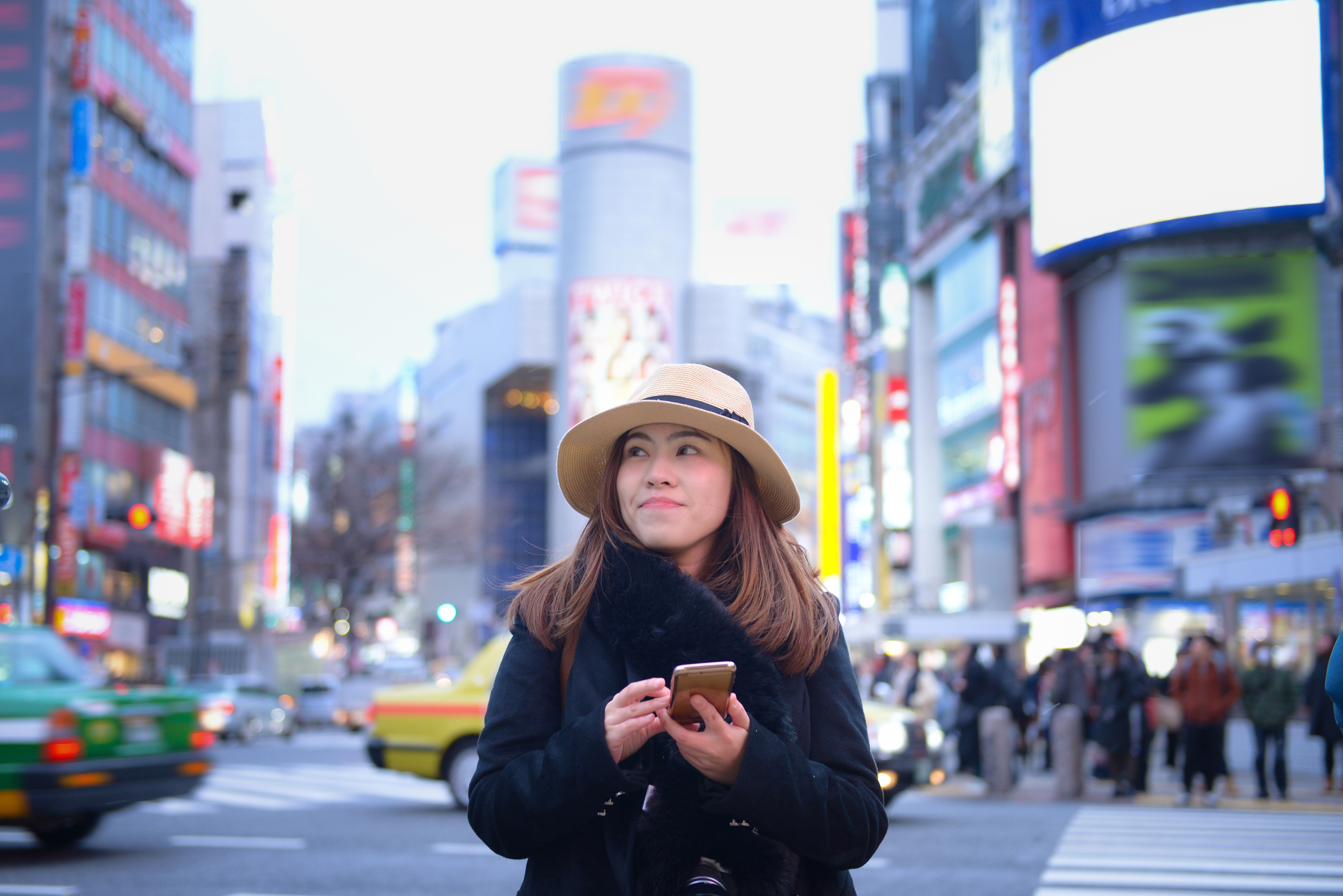 Woman tourist is using smart phone at Shibuya cross walk junction.