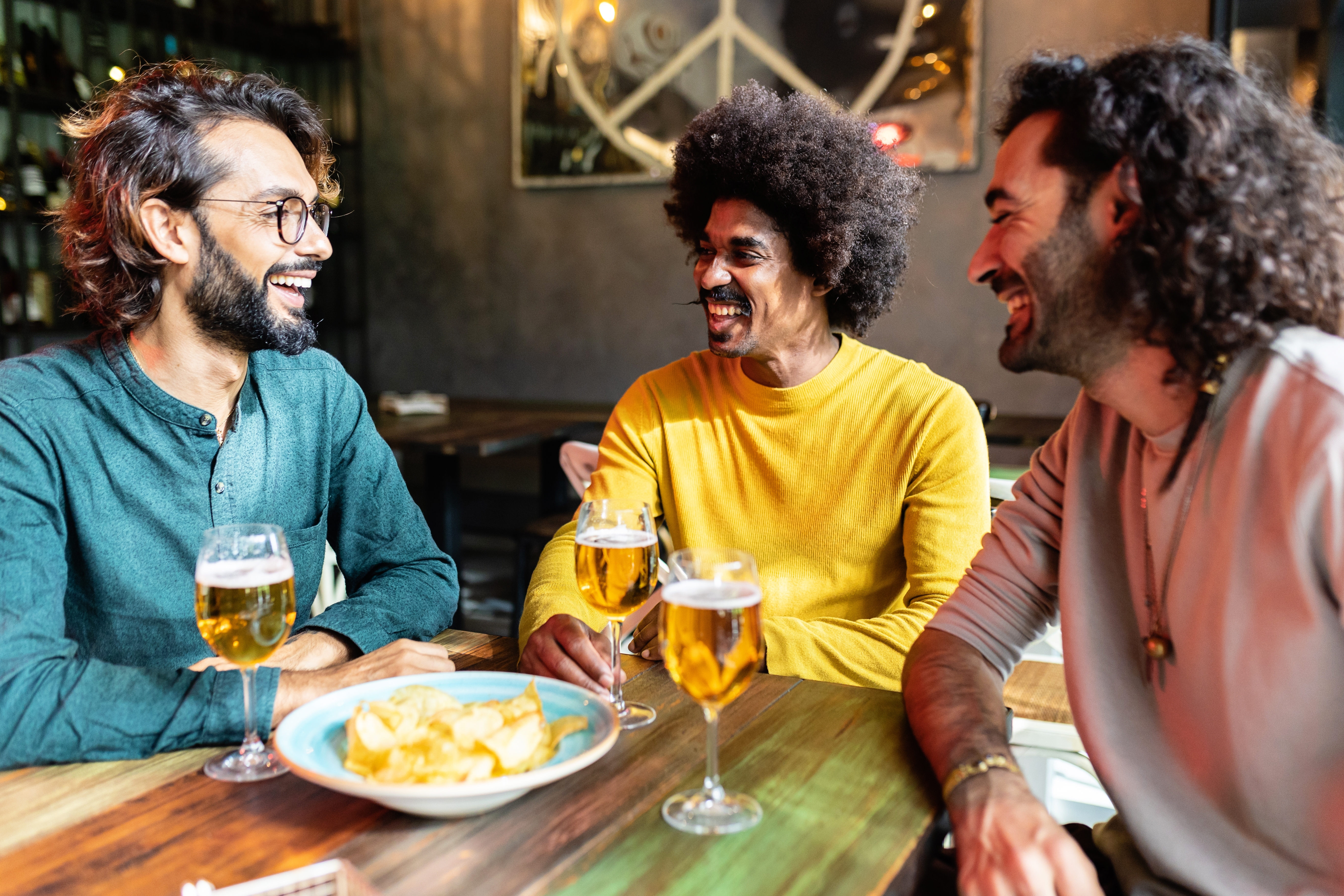 Three male friends are sharing a joyful moment at a bar