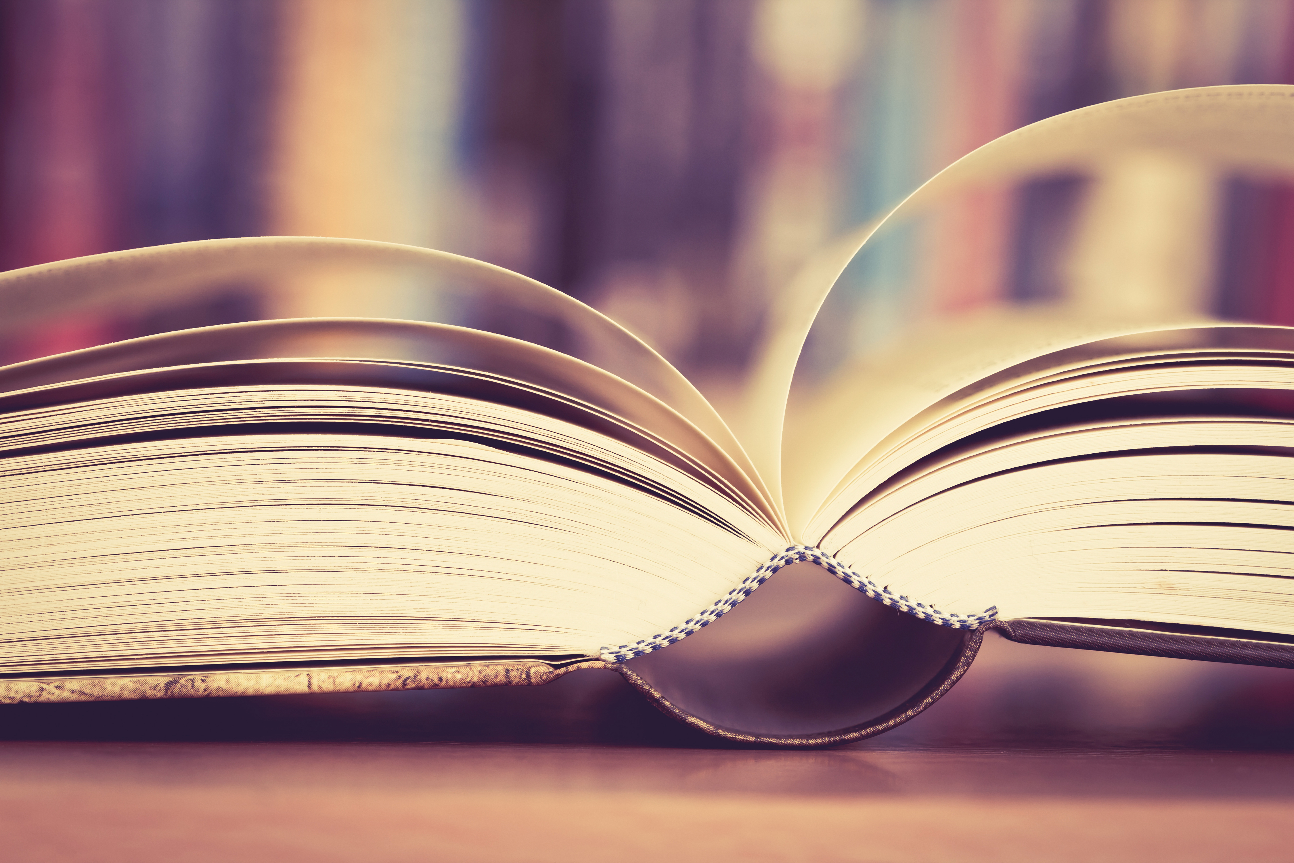 Close up opened book page with blurry bookshelf background for education and publication concept , extremely DOF with vintage retro color tone