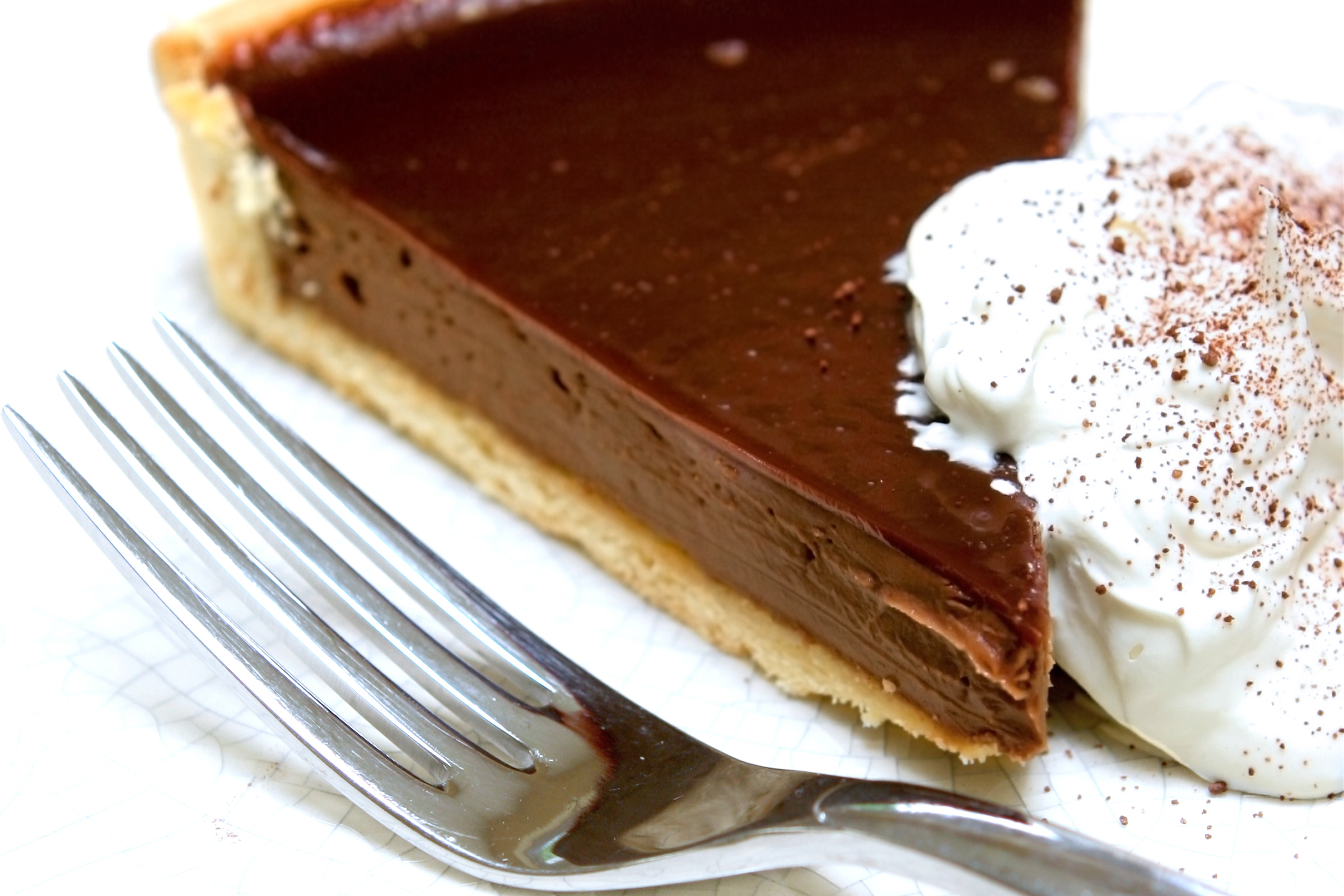 A slice of delicious chocolate tart gateaux served with fresh whipped cream with sprinkling of chocolated dust.