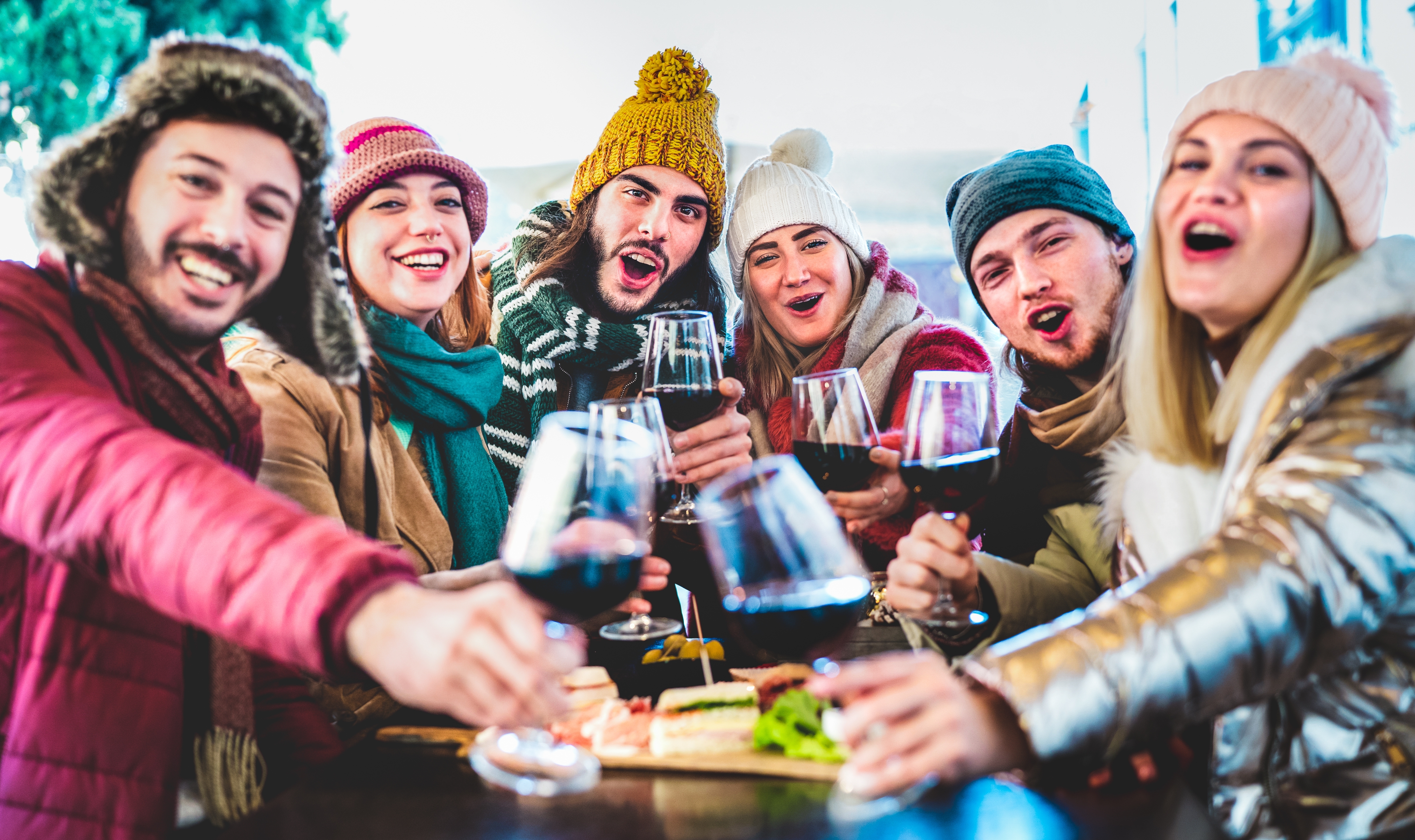 Young trendy friends toasting red wine at restaurant garden out side