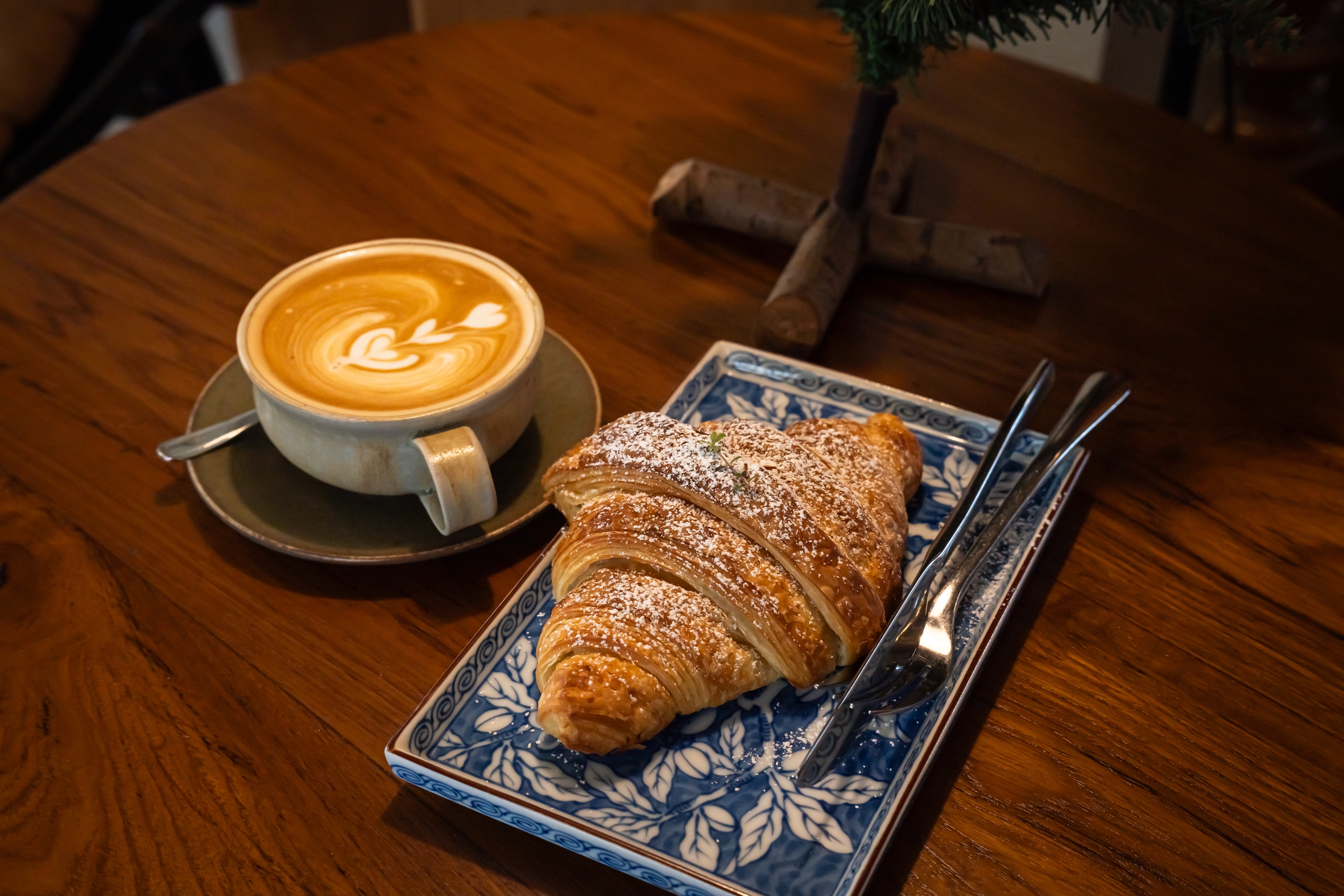 Hot coffee latte with latte art milk foam in cup mug with Croissant on wood desk on top view. As breakfast In a coffee shop at the cafe,during business work concept,vintage style