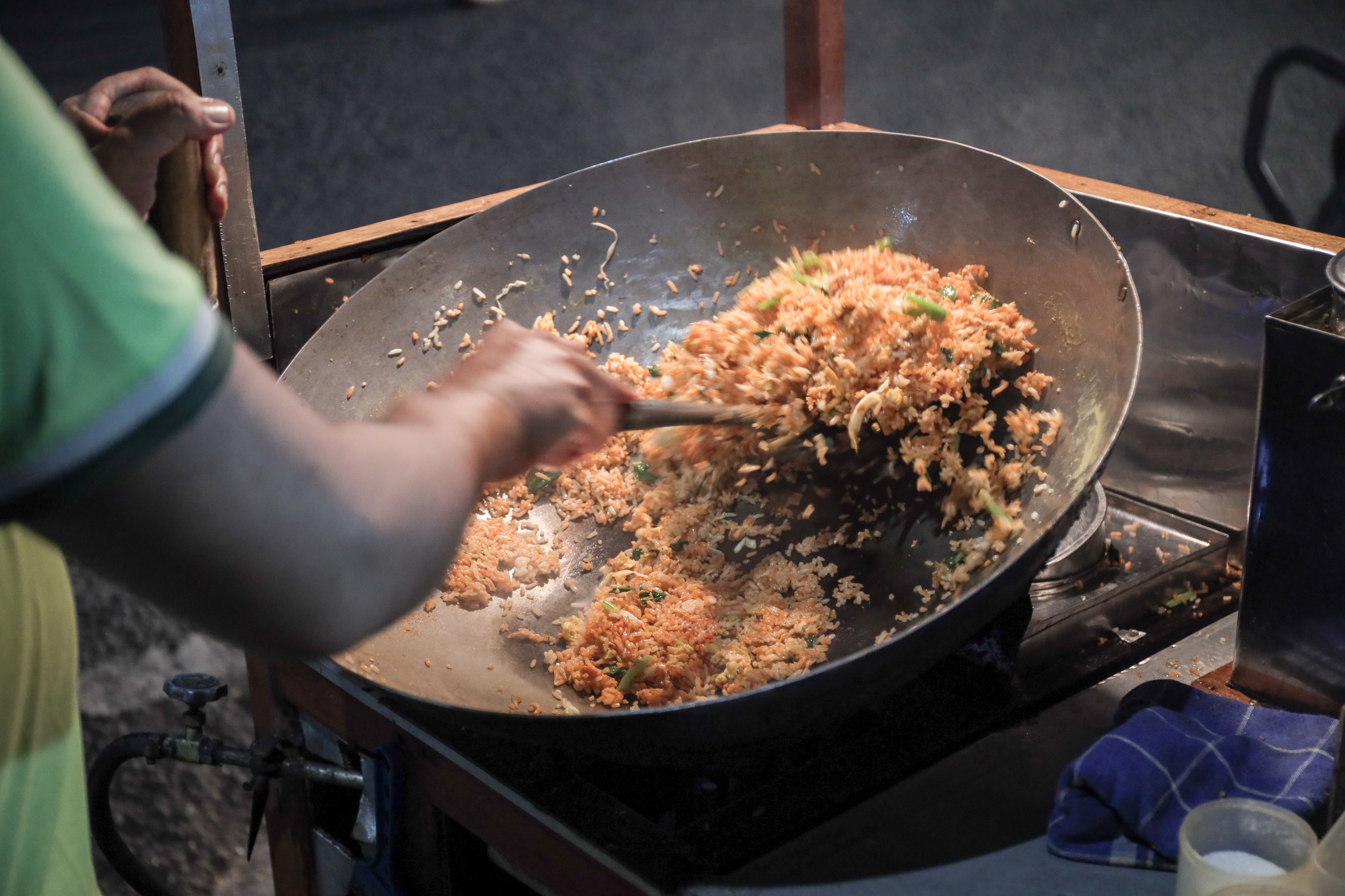 A man cooking fried rice on steel skillet pan for selling on the street food. Indonesian call the dish Nasi Goreng. Indonesian Street food culinary