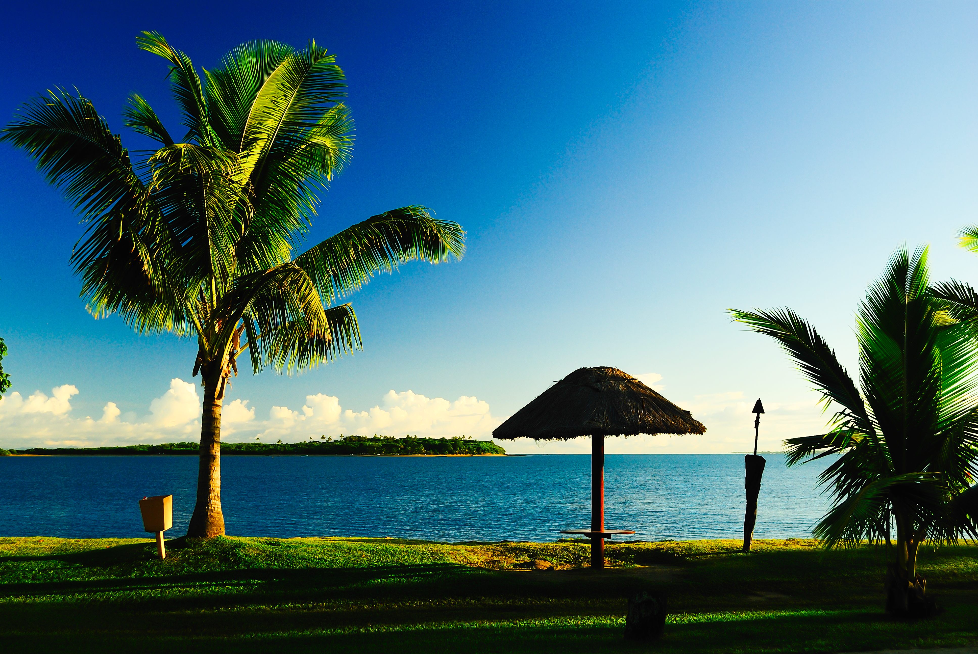 Enjoying clear blue sky sunrise in sandy beach of Denarau Island in Fiji for family friend quiet peaceful holiday and wedding couple honey moon retreat with huts and palm trees