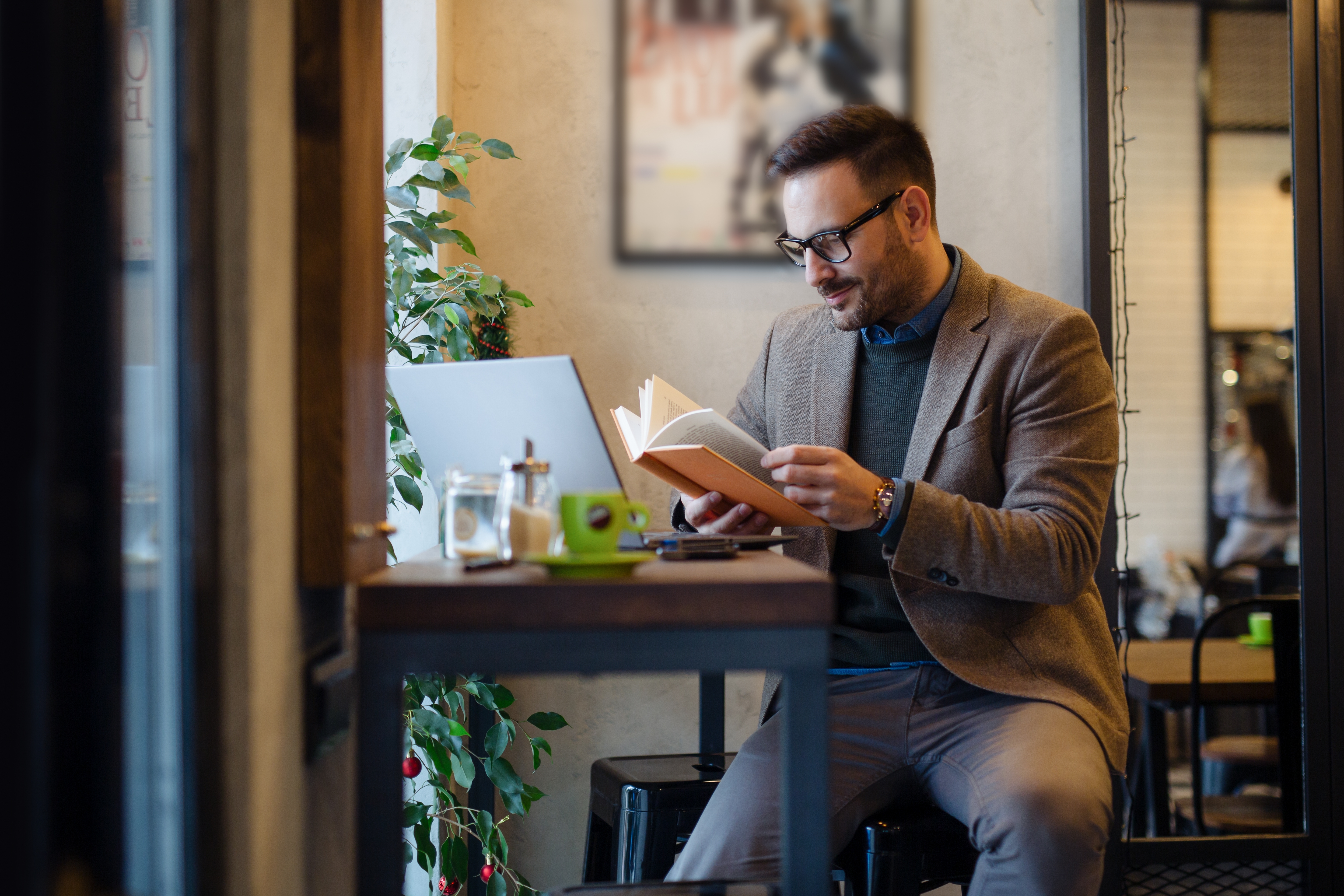 Businessman Reading Book while Sitting in Cafe