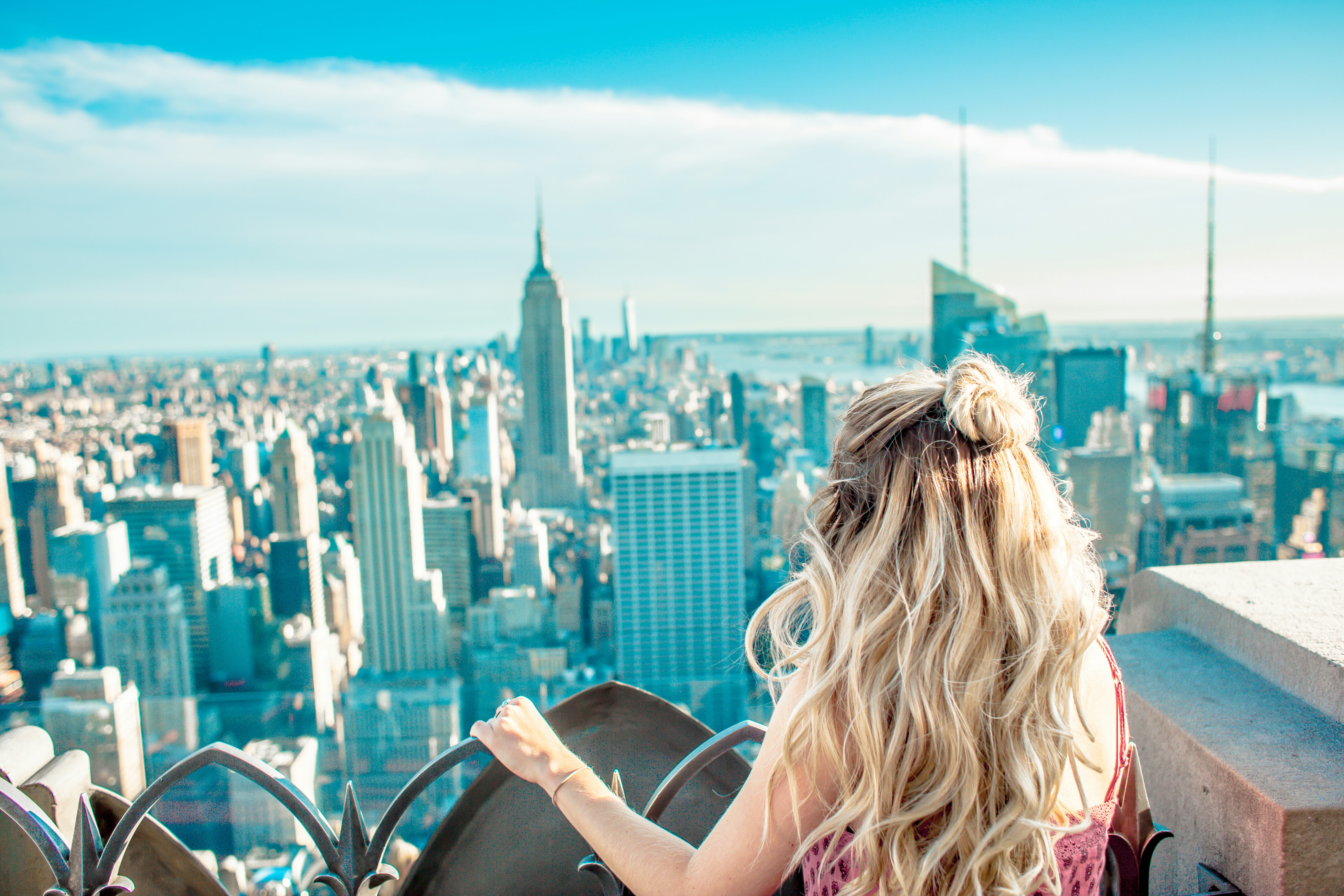 blonde woman at the rooftop of a building overlooking the skyline in New York City