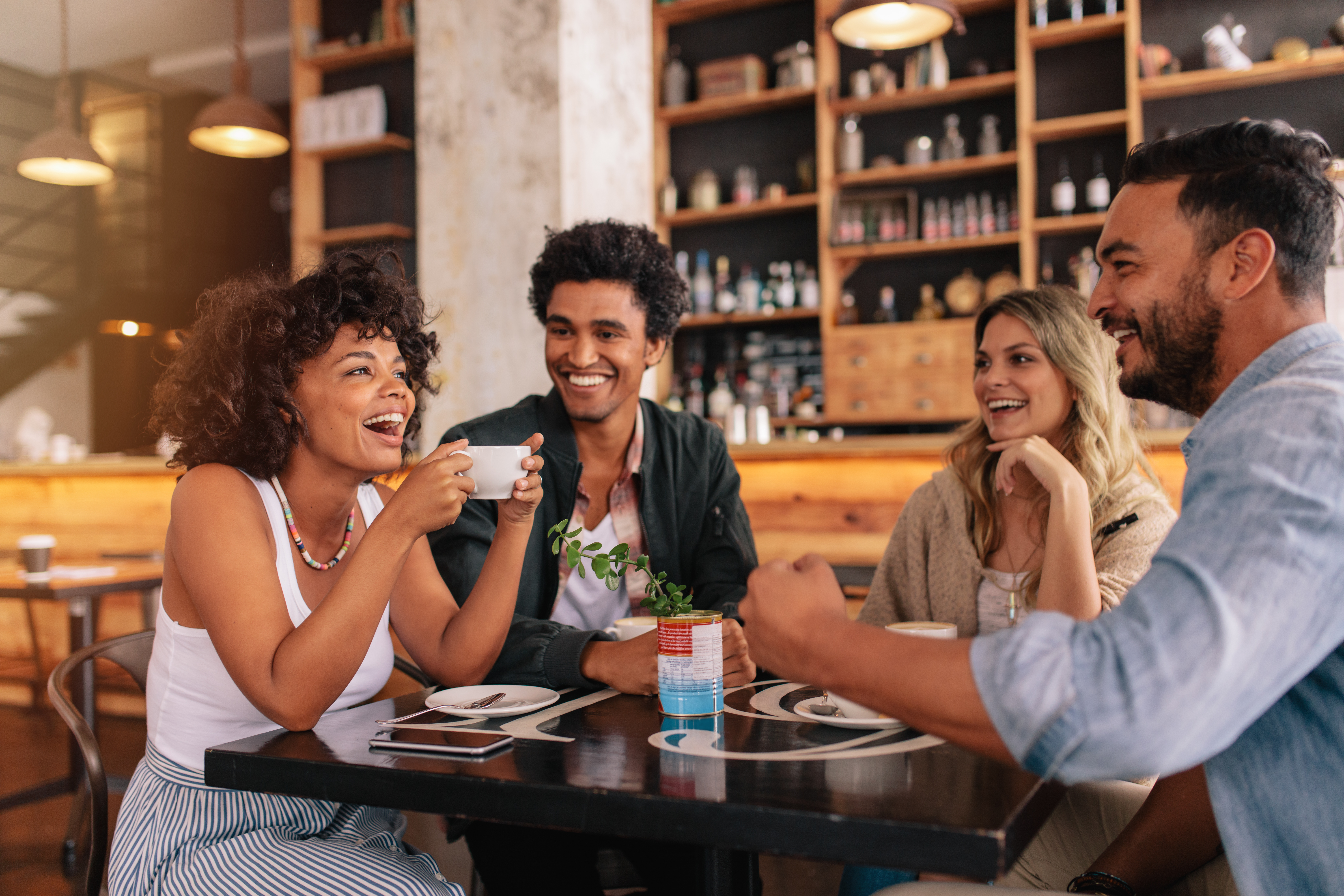 Young friends having a great time in restaurant. Multiracial group of young people sitting in a coffee shop and smiling.