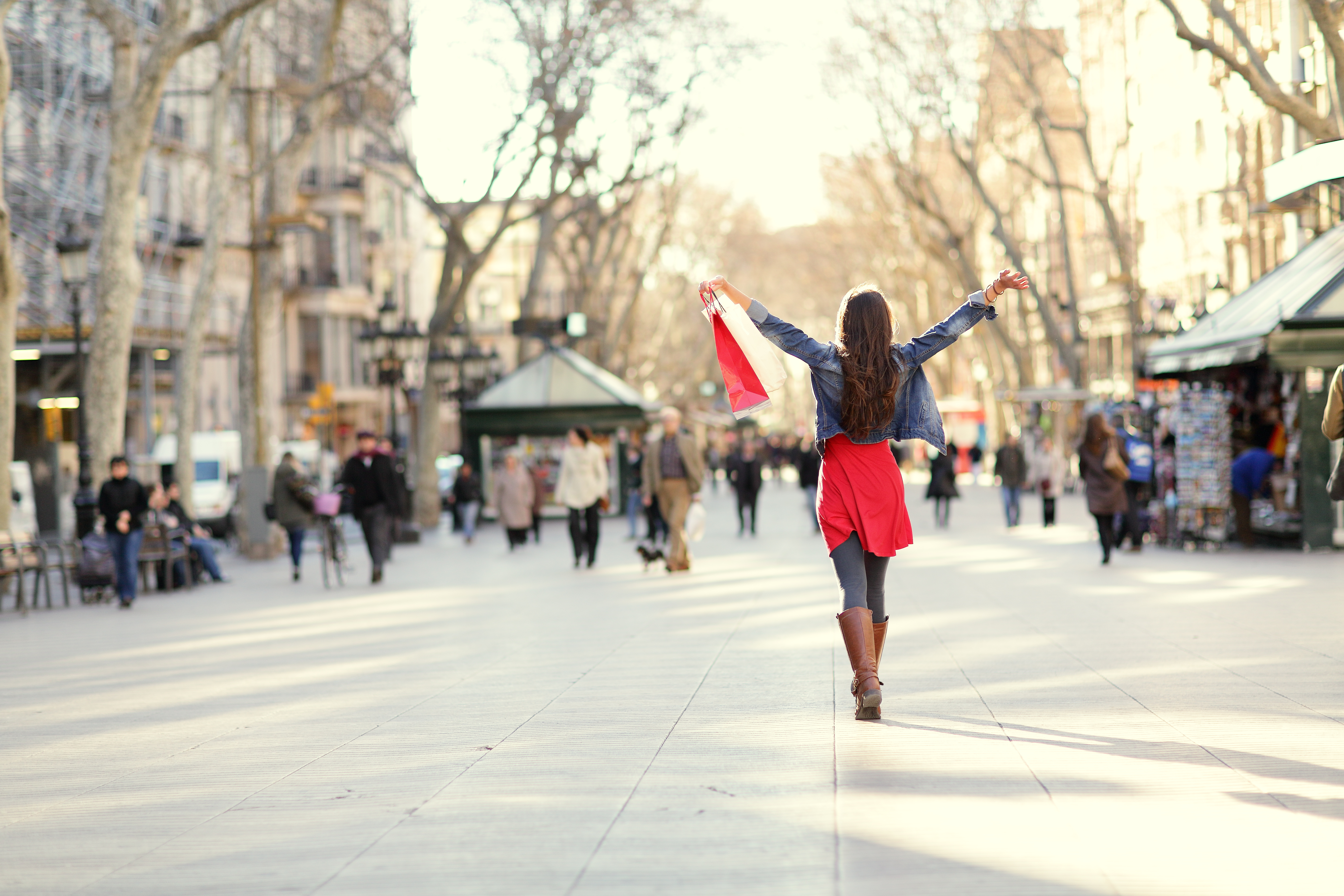 Barcelona, La Rambla shopping woman. Female shopper walking happy away with shopping bags raised up. From the famous landmark street in Catalonia, Spain.