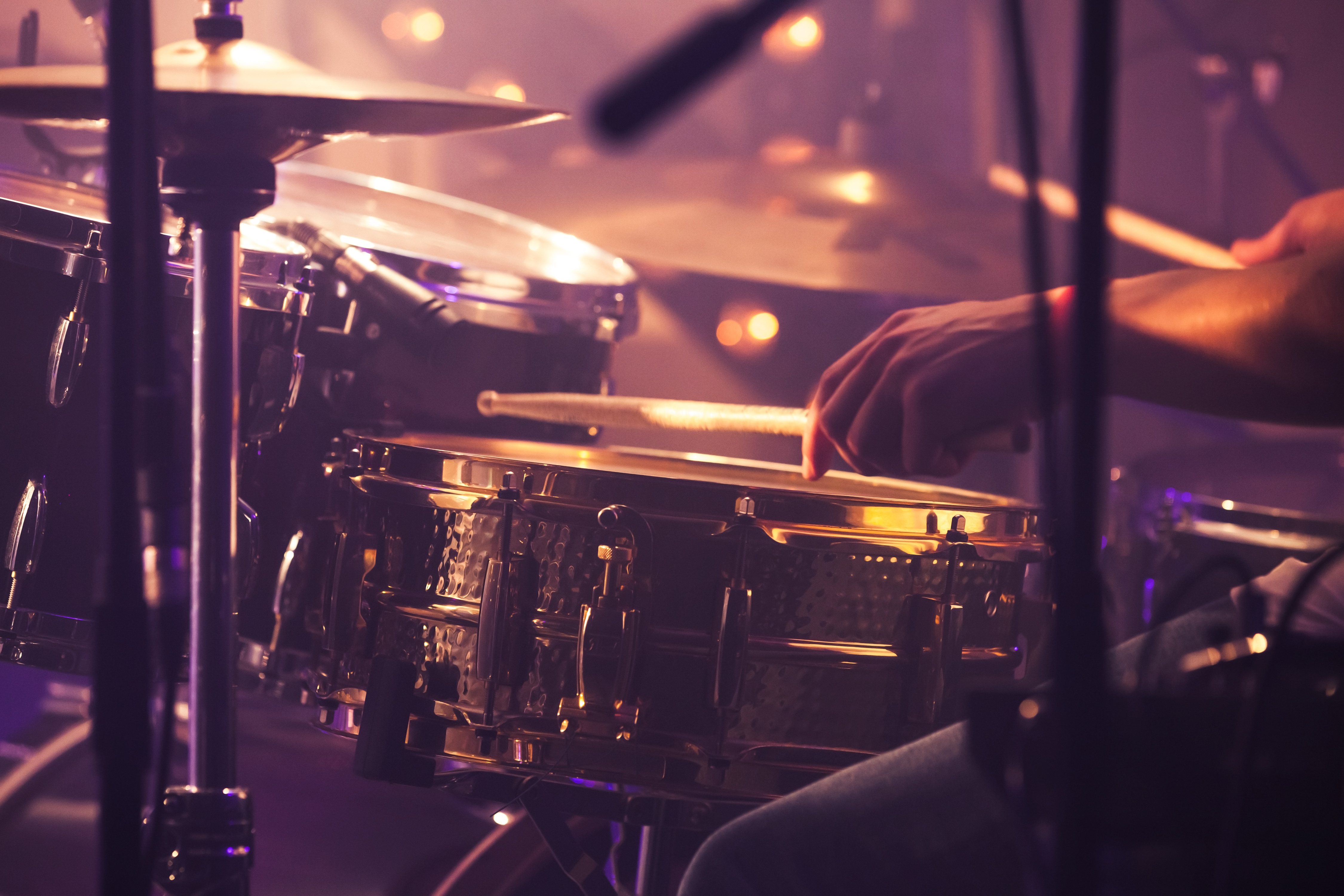 Vintage toned live music background, drummer plays with drumsticks on rock drum set. Closeup photo with soft selective focus