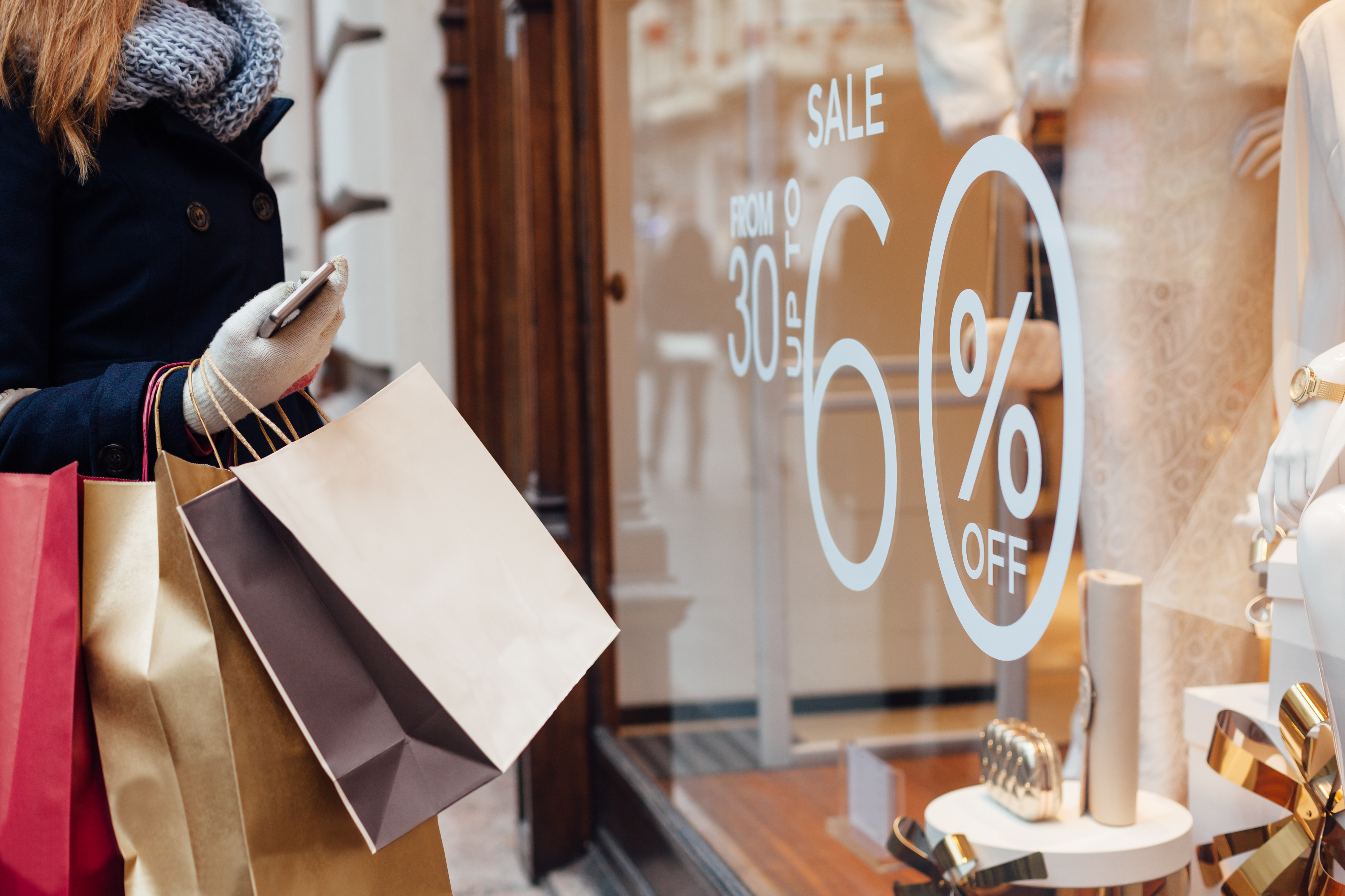 Closeup of woman with shopping bags in front on store window
