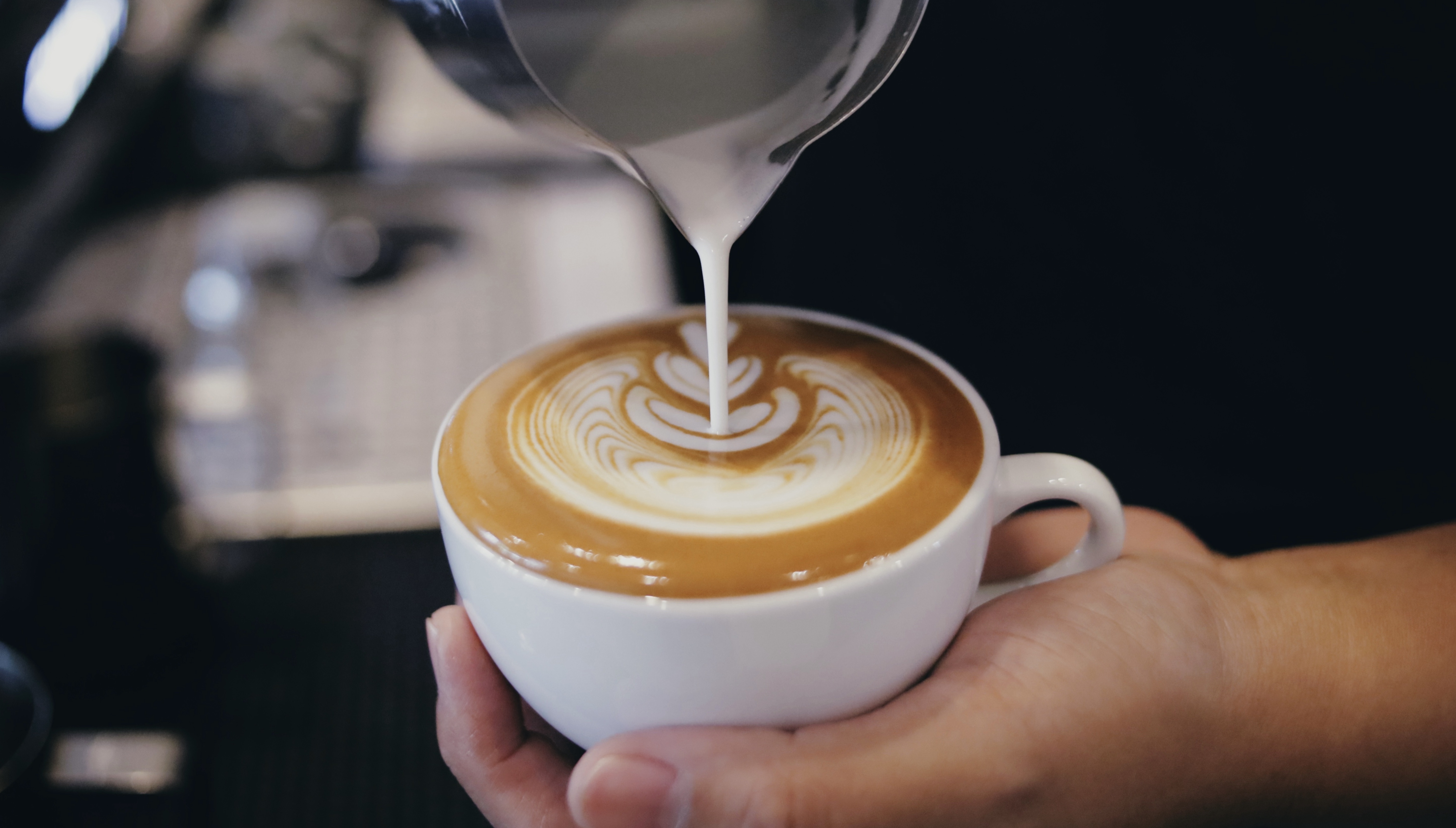 Barista pouring milk into a coffee mug
