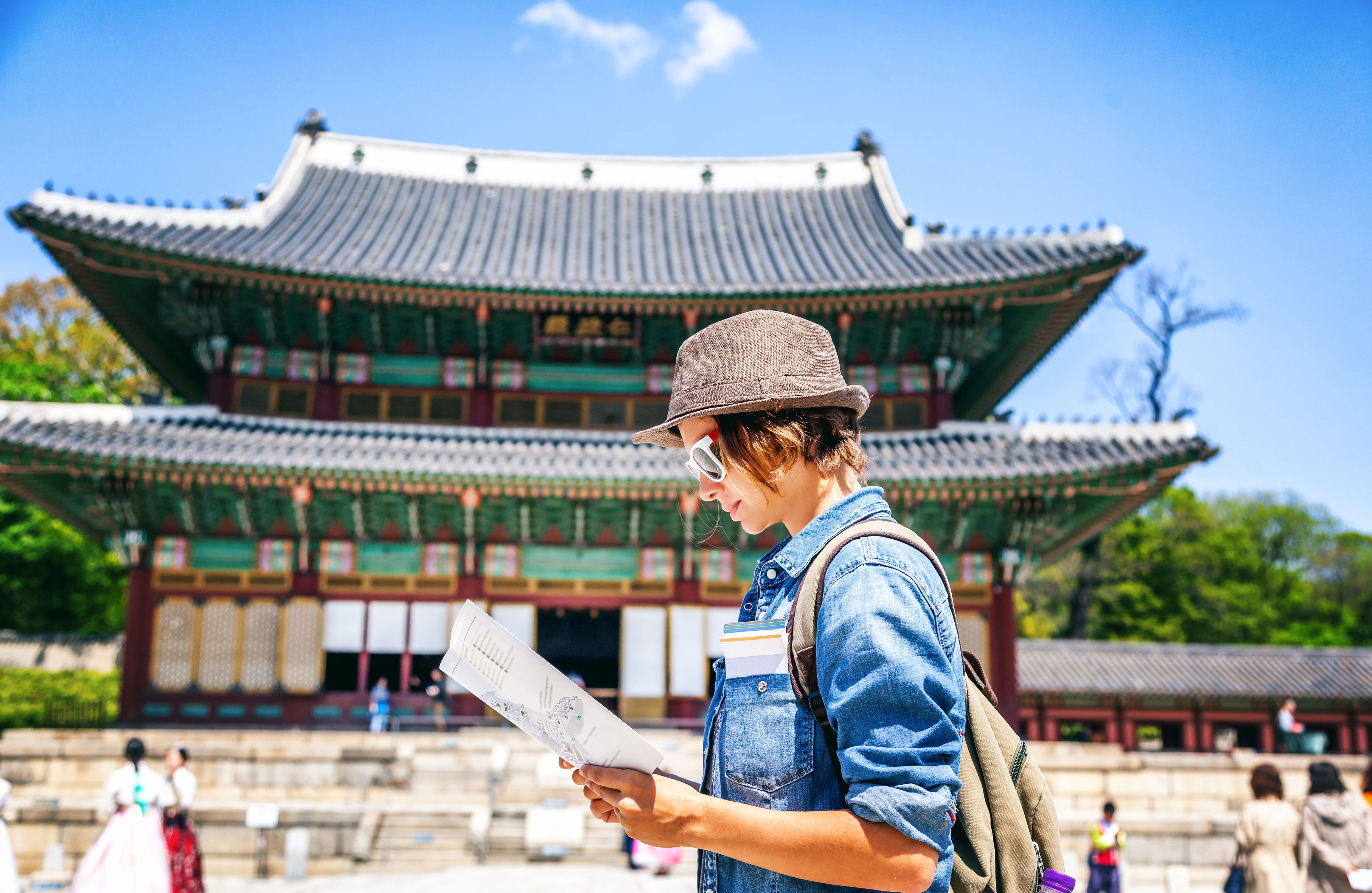 Young woman tourist with map in hand on the background of Asian architecture, travel to Korea, Seoul Asia