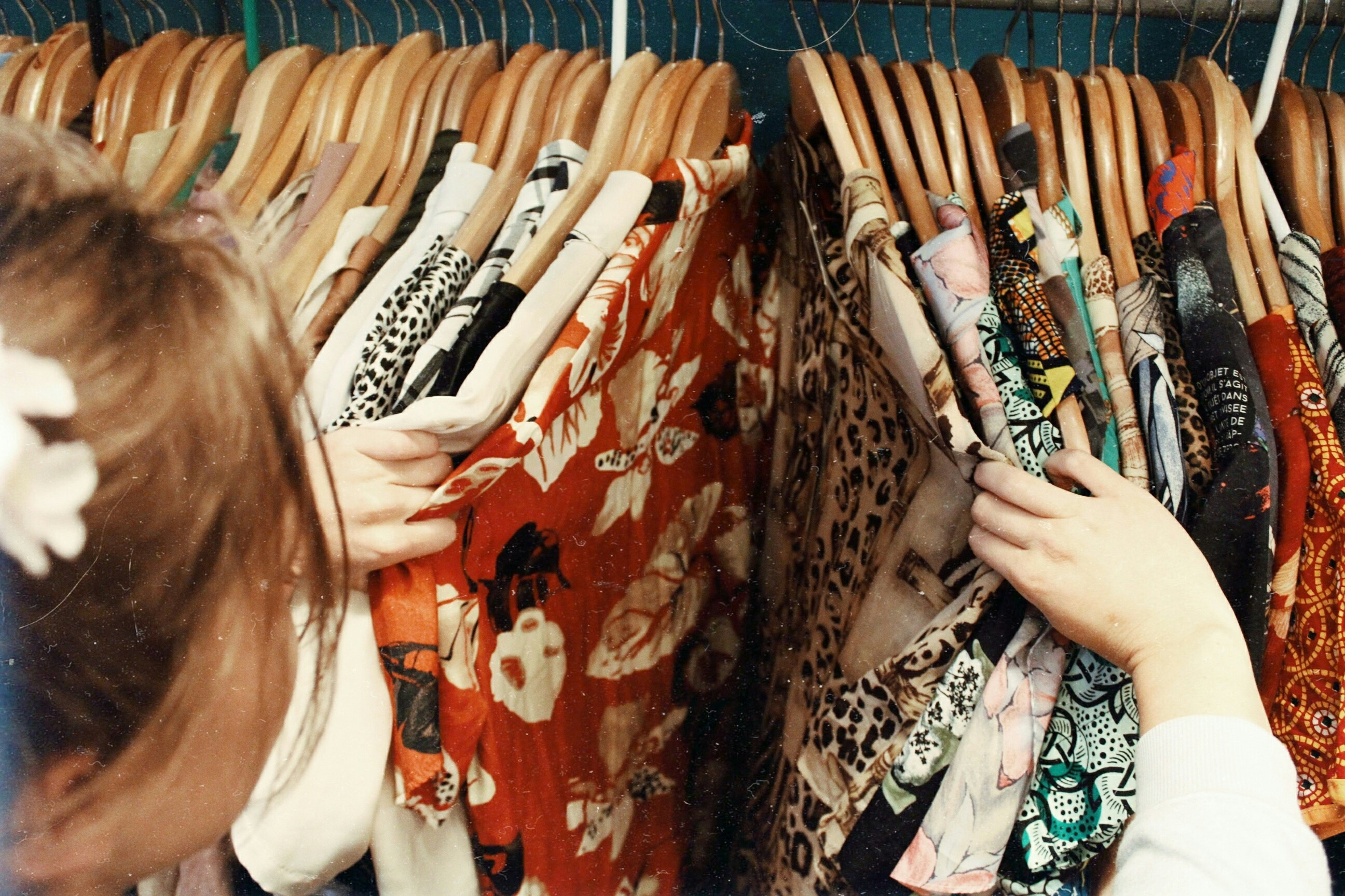 woman going through assorted colourful clothes in wooden hanger