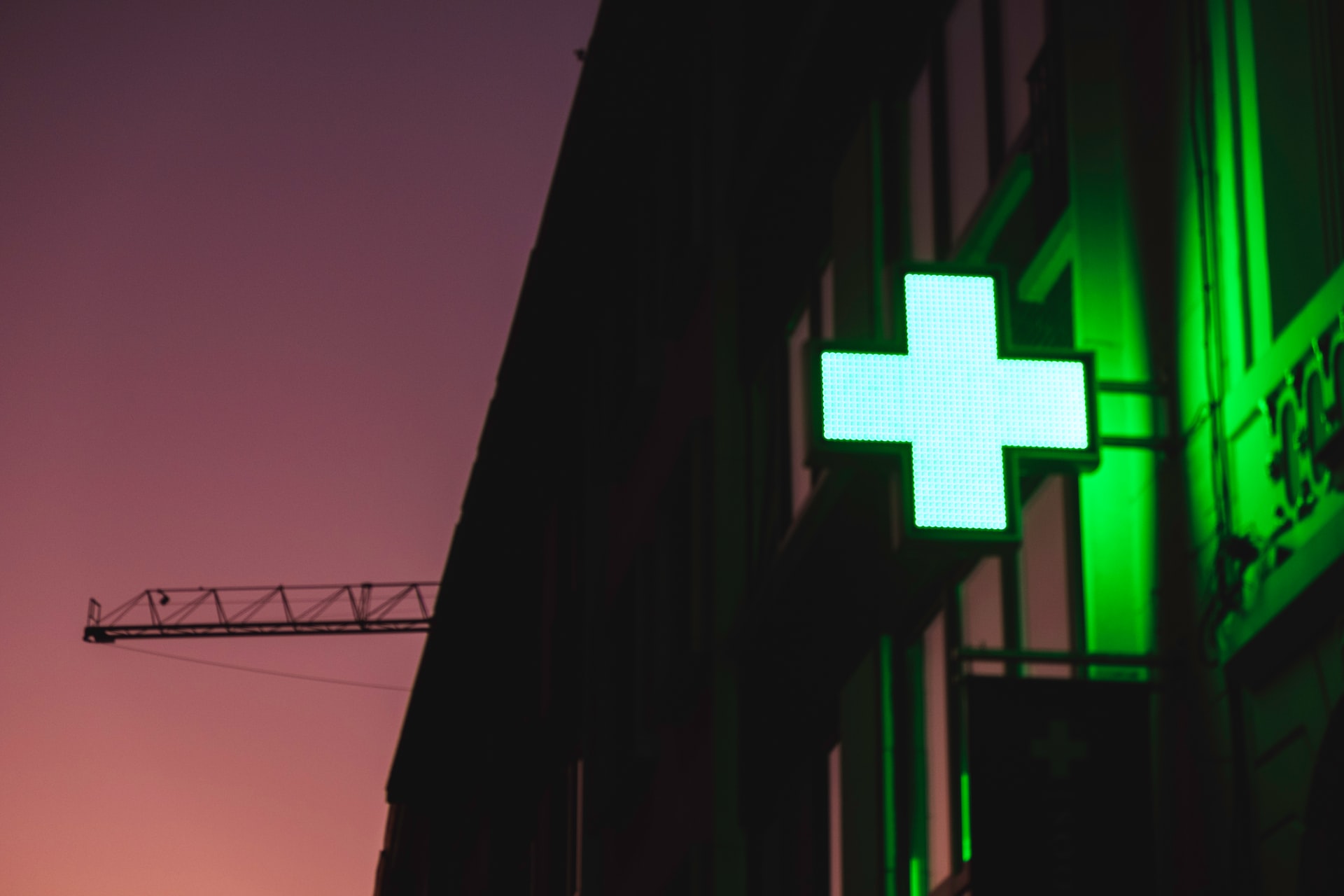 pharmacy green cross on building in evening