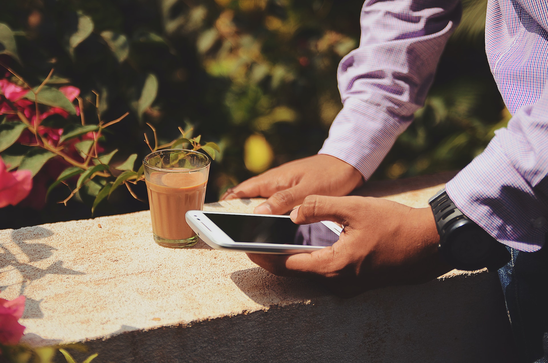 man using smartphone next to coffee