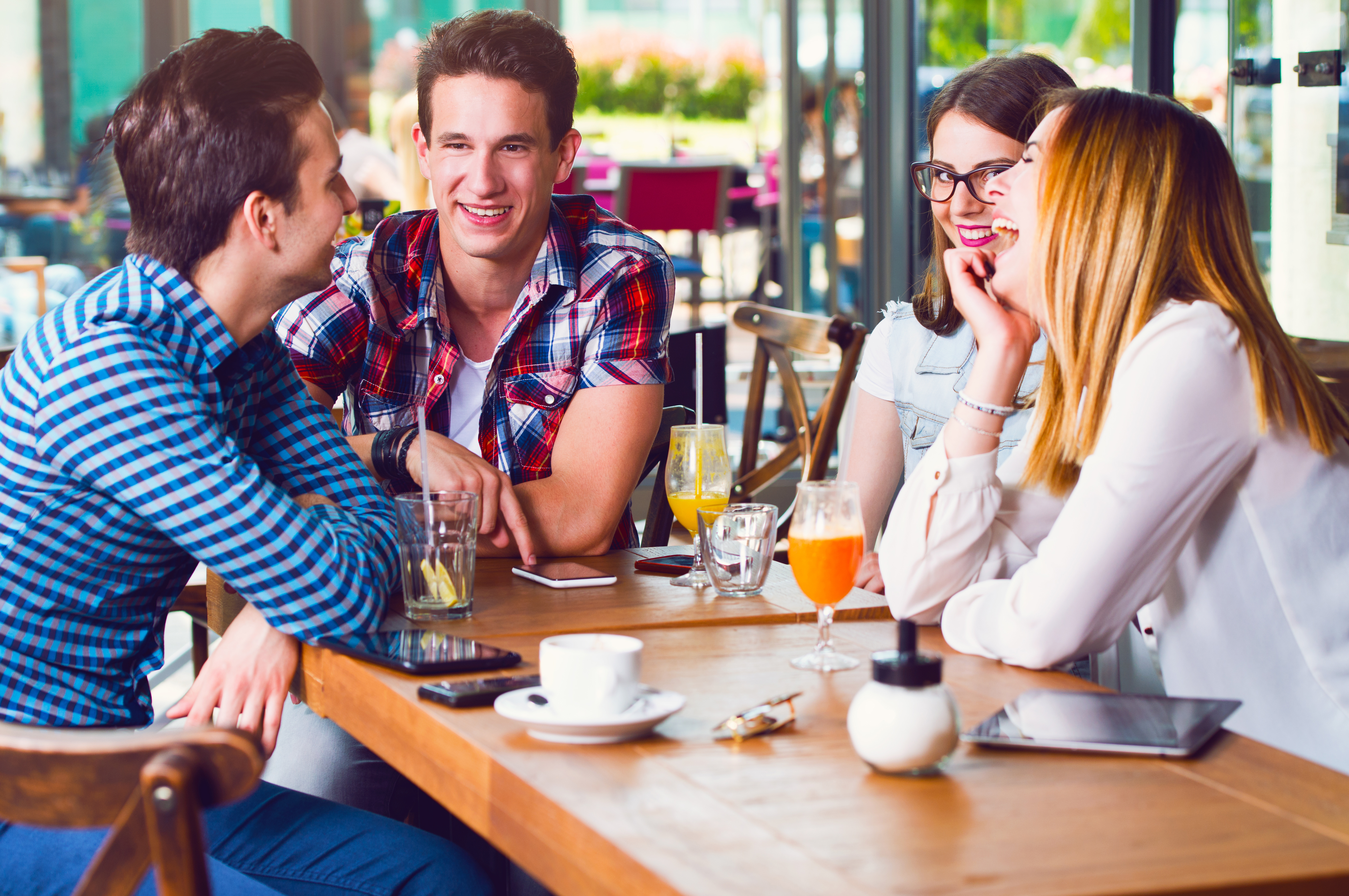 Group of young people sitting at a cafe, talking and enjoying