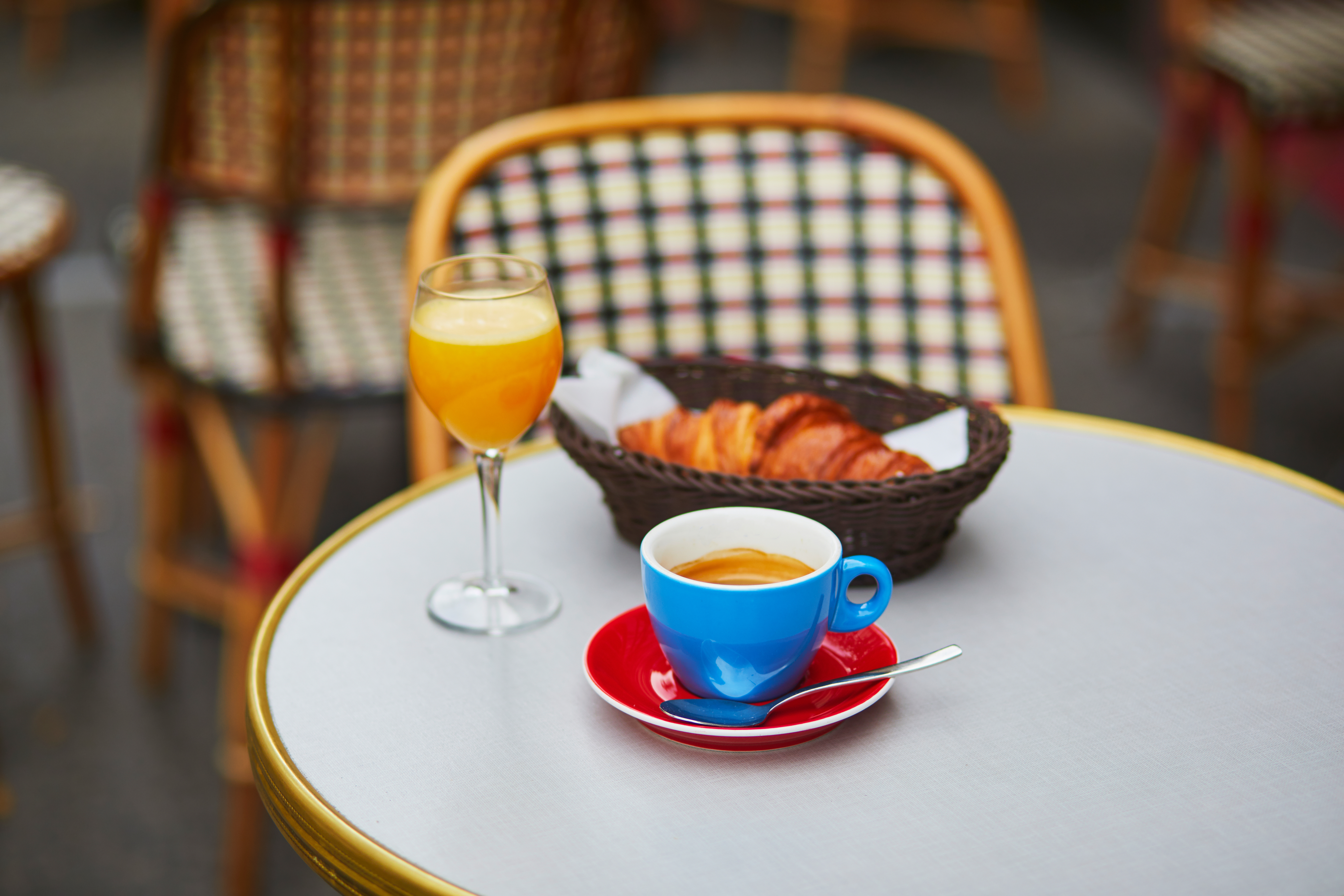 Cup of fresh hot coffee, orange juice and traditional French croissant on table of Parisian outdoor cafe in Paris, France
