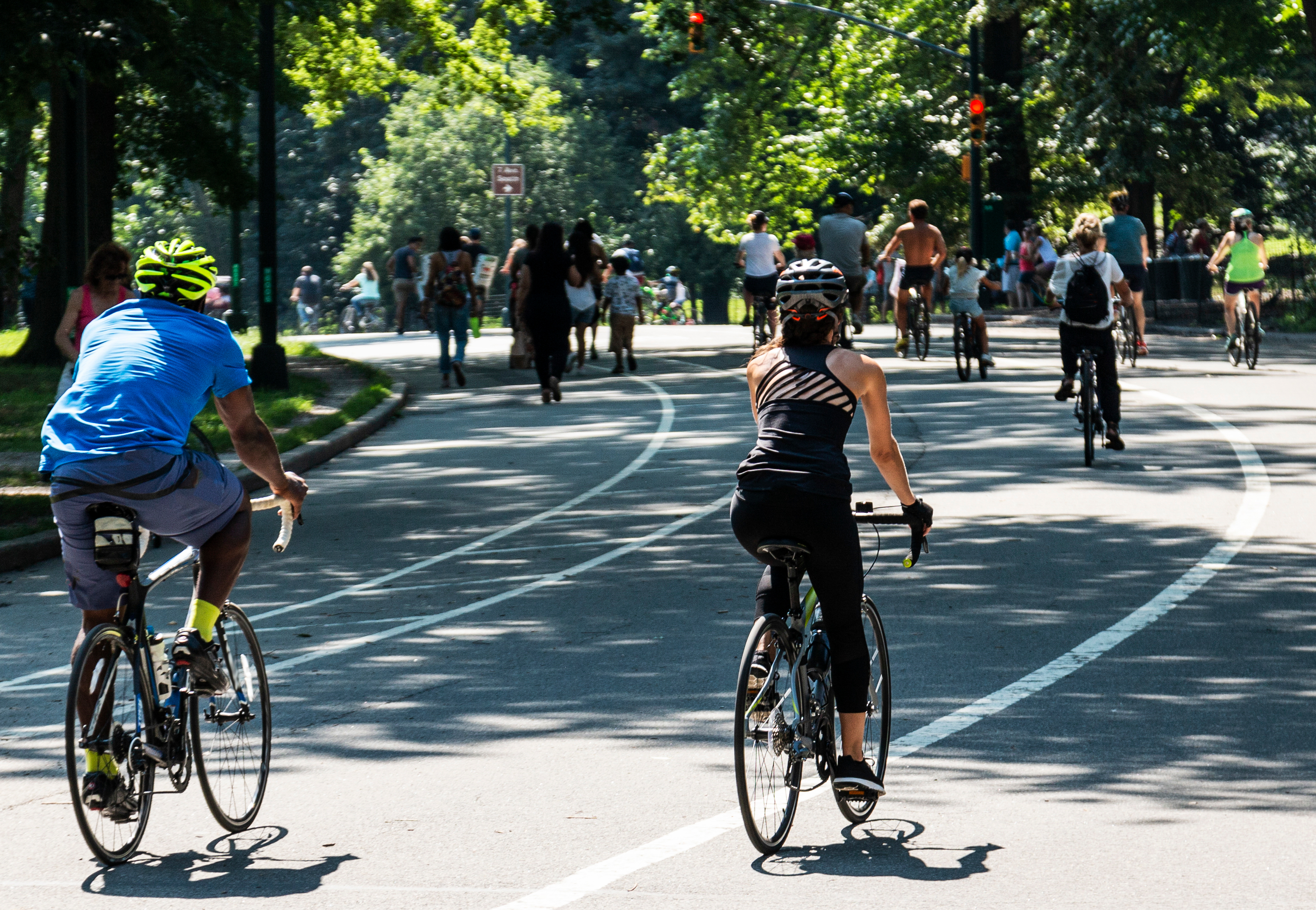 People biking and wlaking around Central Park New York City on a sunny day.