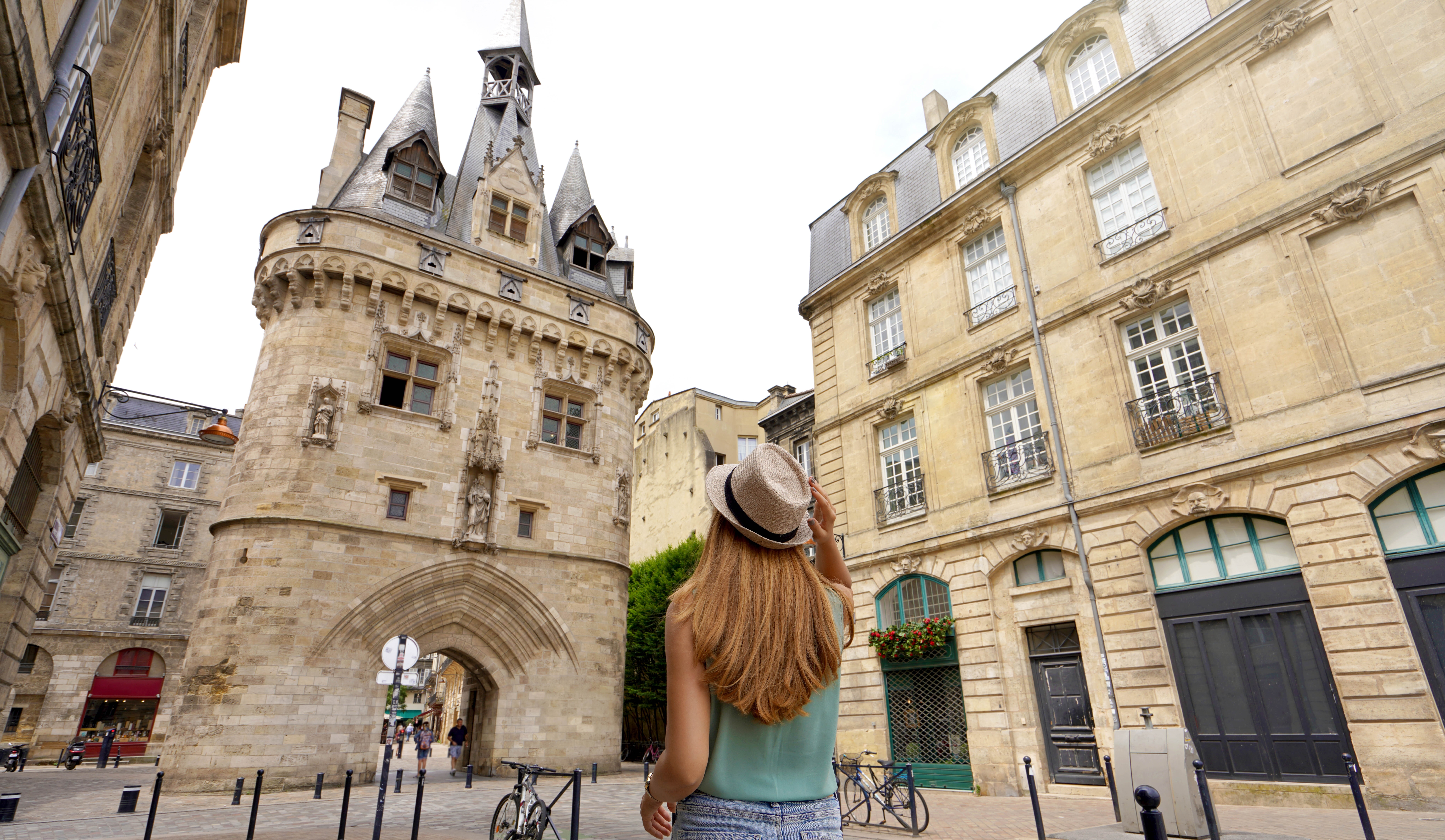 Tourism in Bordeaux, France. Traveler girl walking in Bordeaux discovering Porte Cailhau a medieval gatehouse of the old city walls.