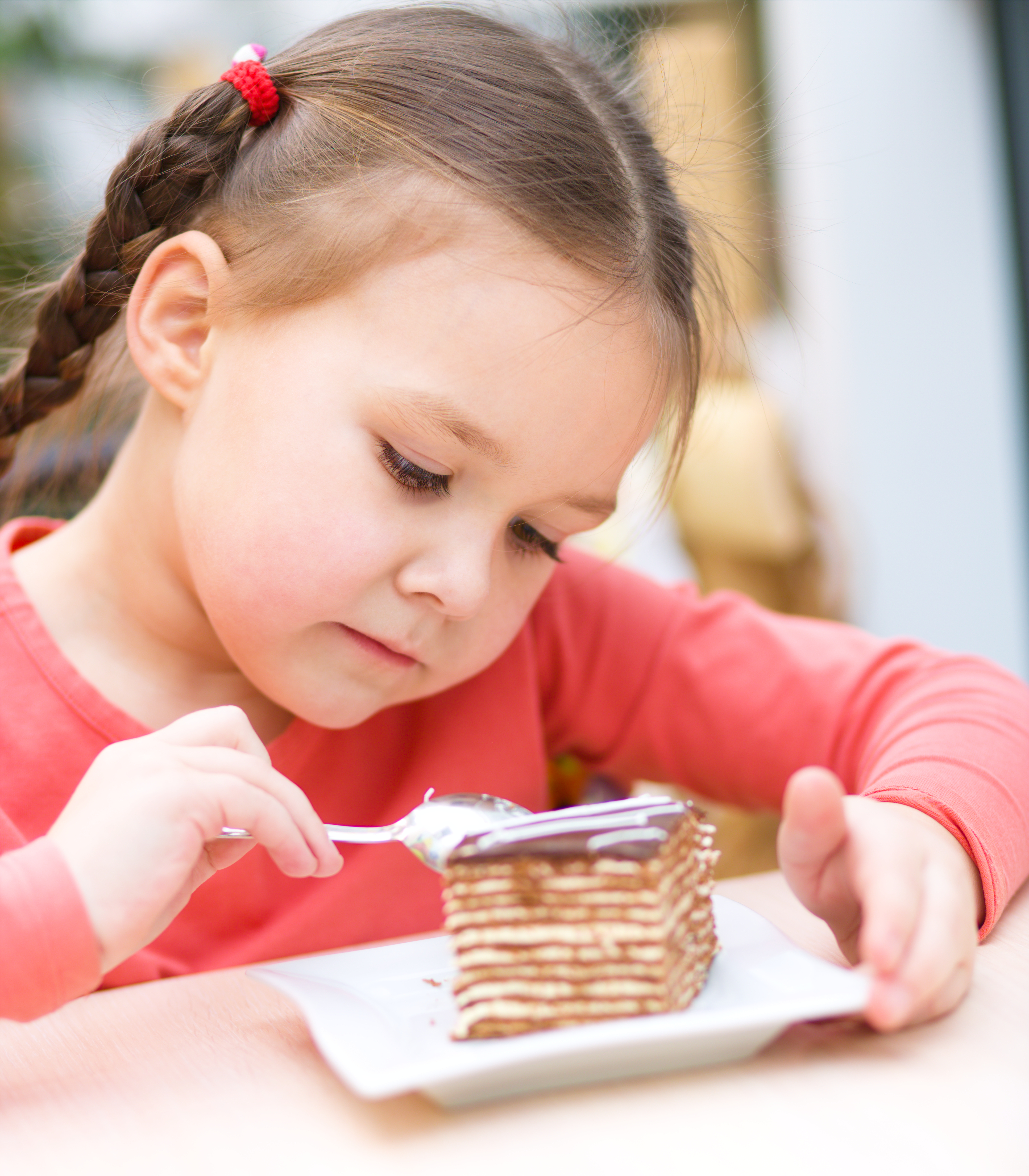 Cute little girl is eating cake in parlor