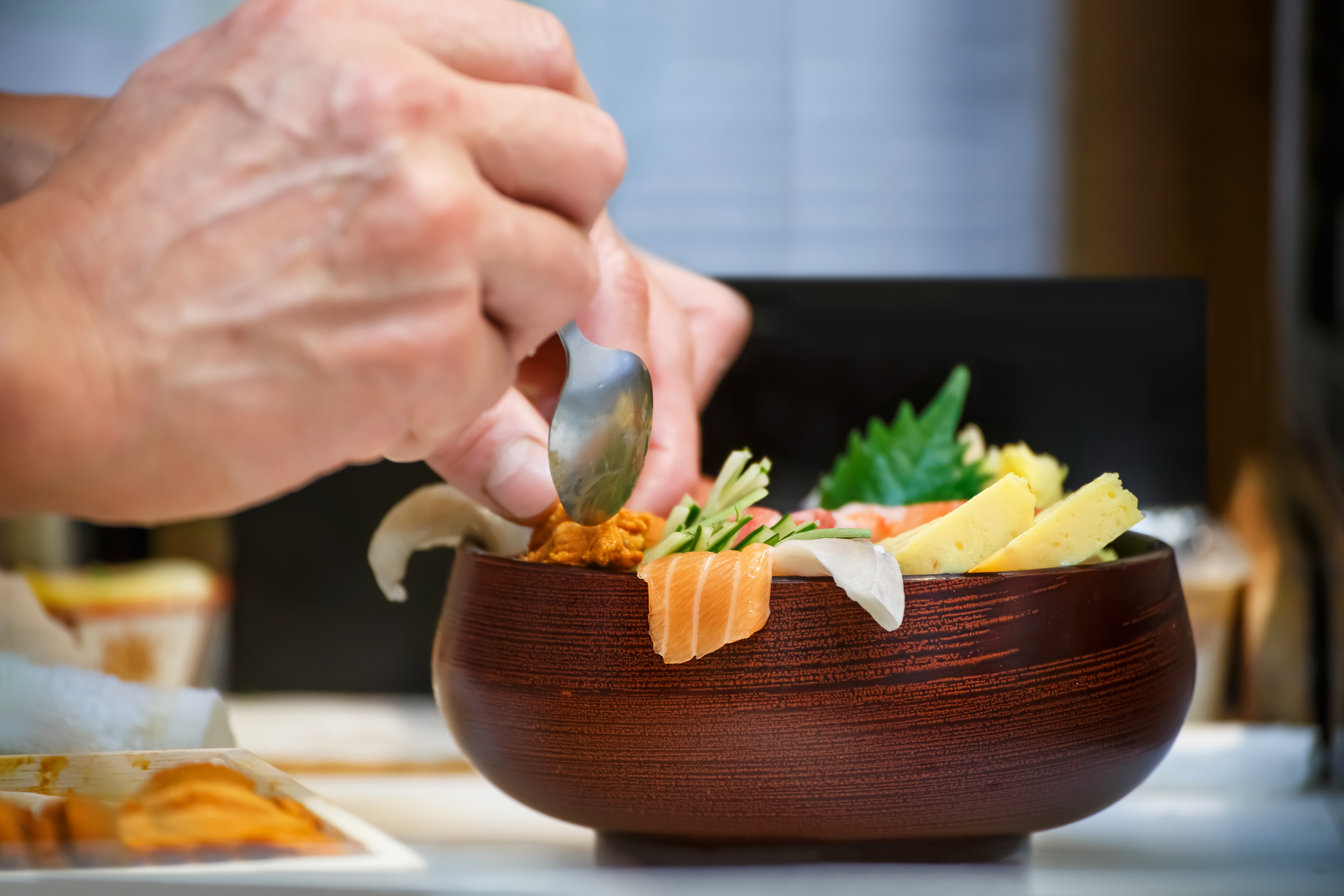 Closeup of a bowl of Sashimi with hands of Japanese chef