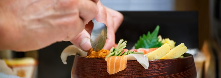 Closeup of a bowl of Sashimi with hands of Japanese chef
