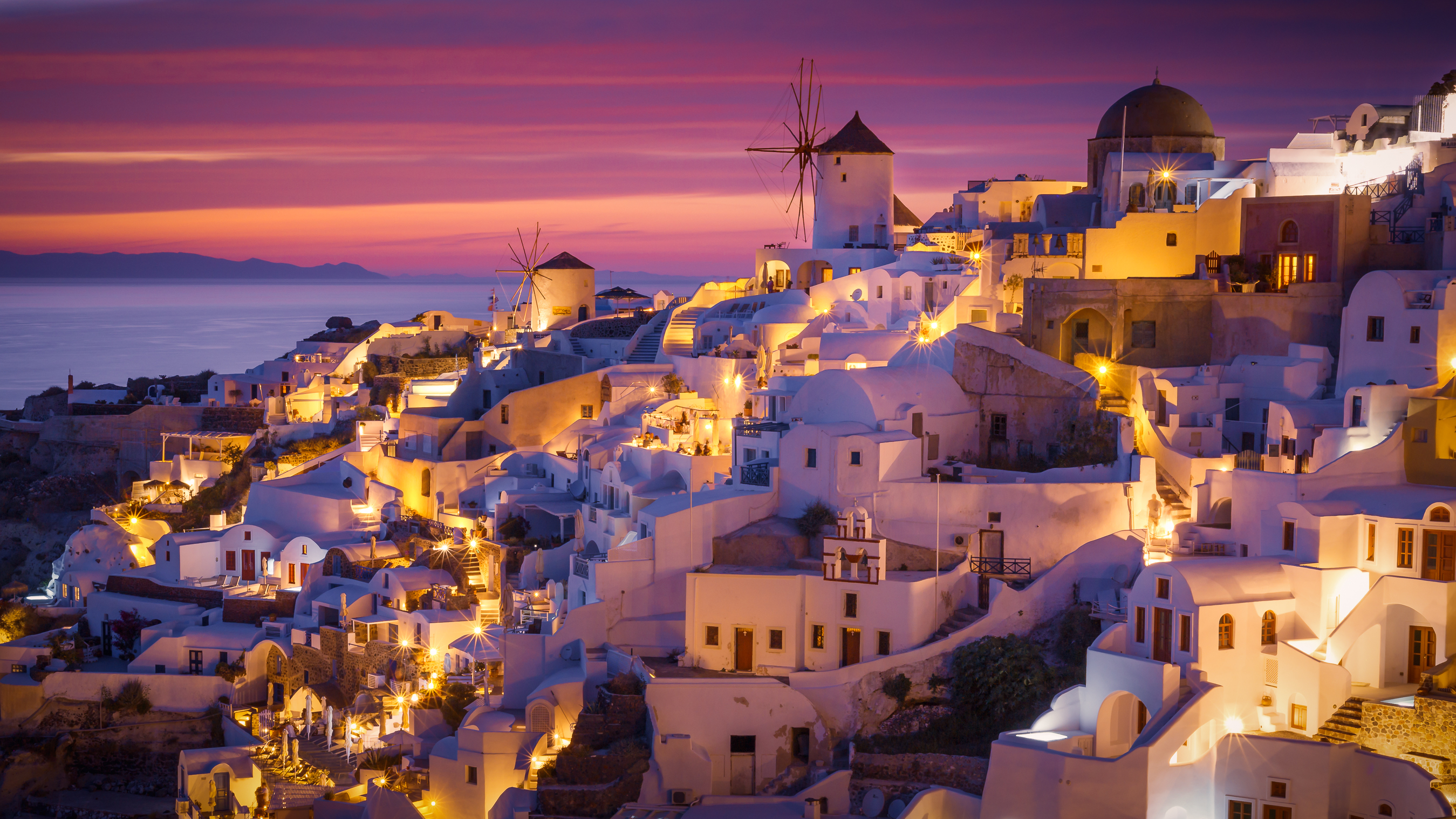 Colorful and Dramatic Sunset with Night Lights in Mediterranean Town of Oia, Santorini, Greece, Europe