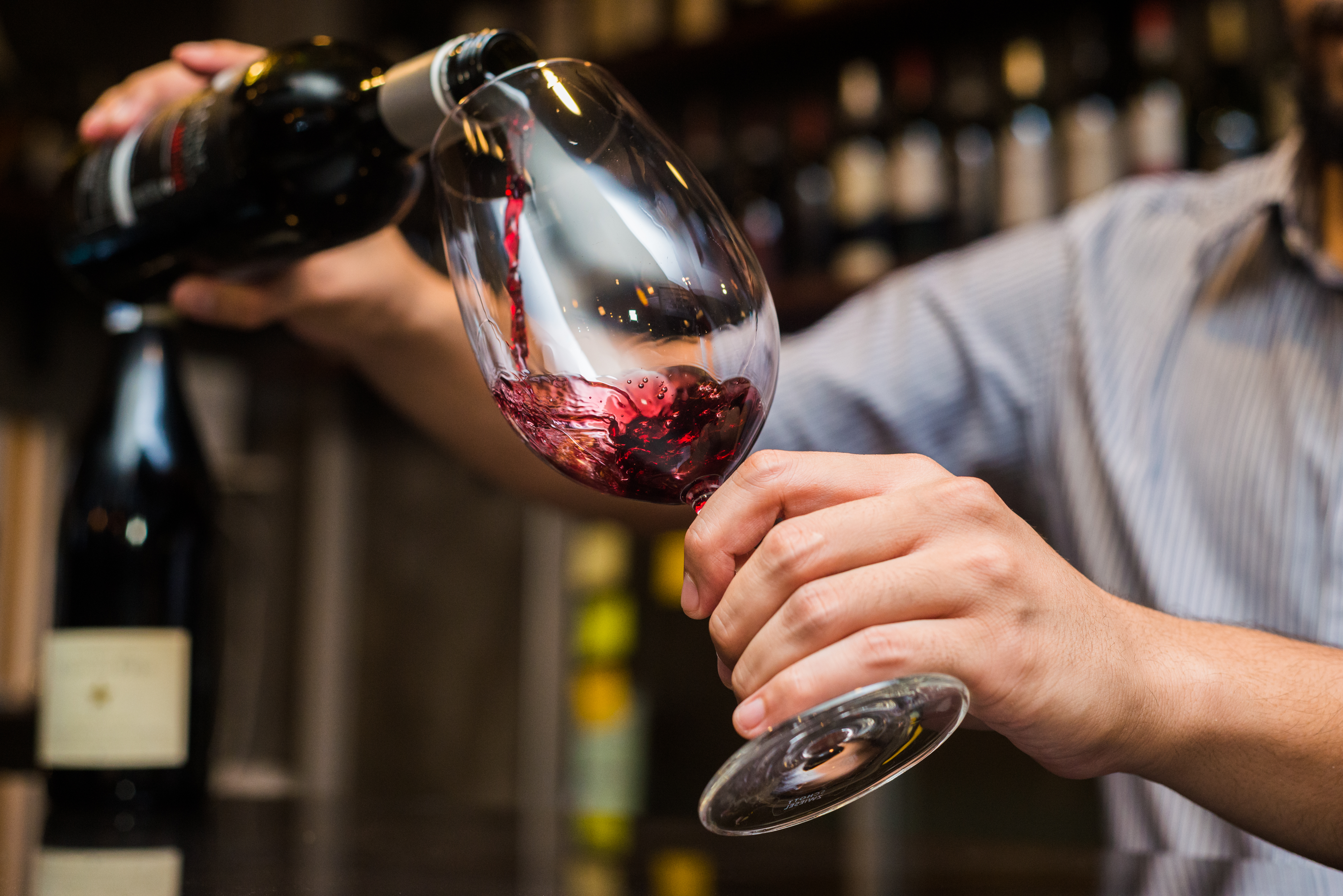 Bartender pouring red wine in a glass