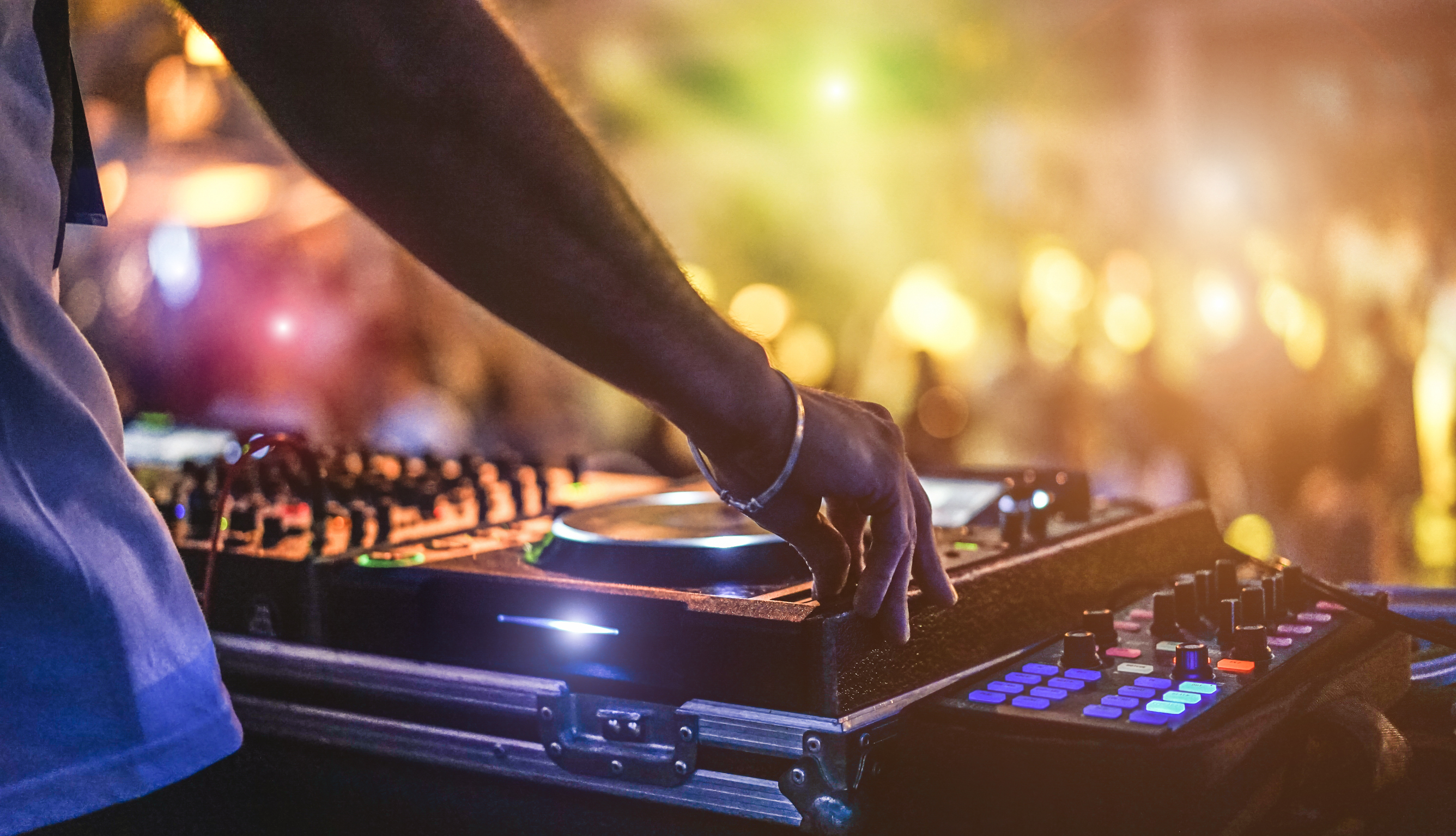 Dj mixing outdoor at beach party festival with crowd of people in background - Summer nightlife view of disco club outside - Soft focus on hand - Fun, youth, entertainment and fest concept - Bild