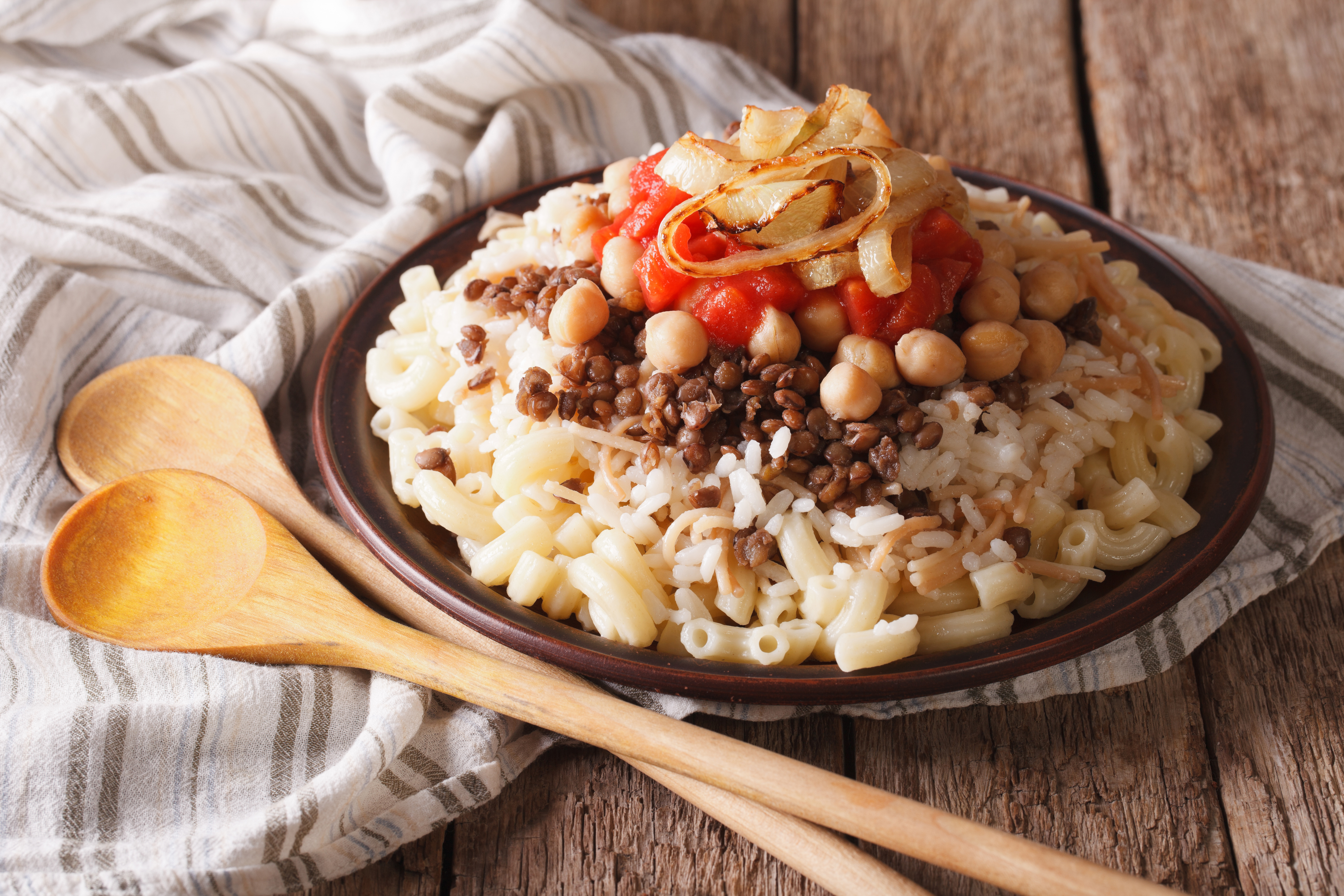 Arabic cuisine: kushari of rice, pasta, chickpeas and lentils close up on a plate on the table. horizontal